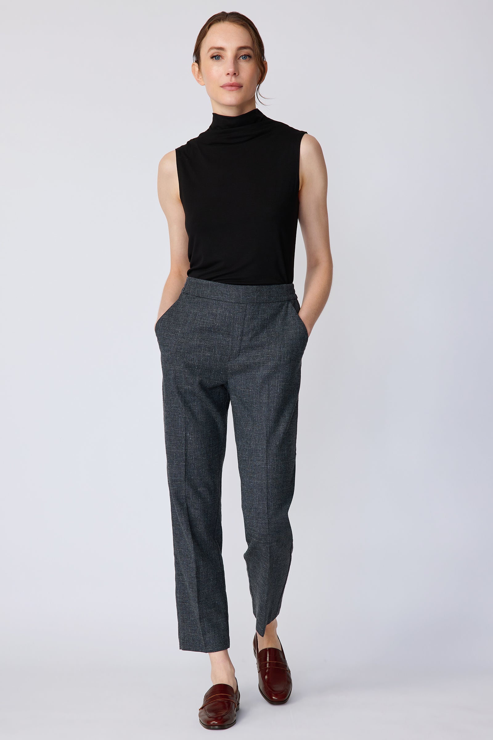 Woman wearing Kal Rieman Martine Trouser in Indigo with brown shoes, hands in pant pockets, on white background, walking