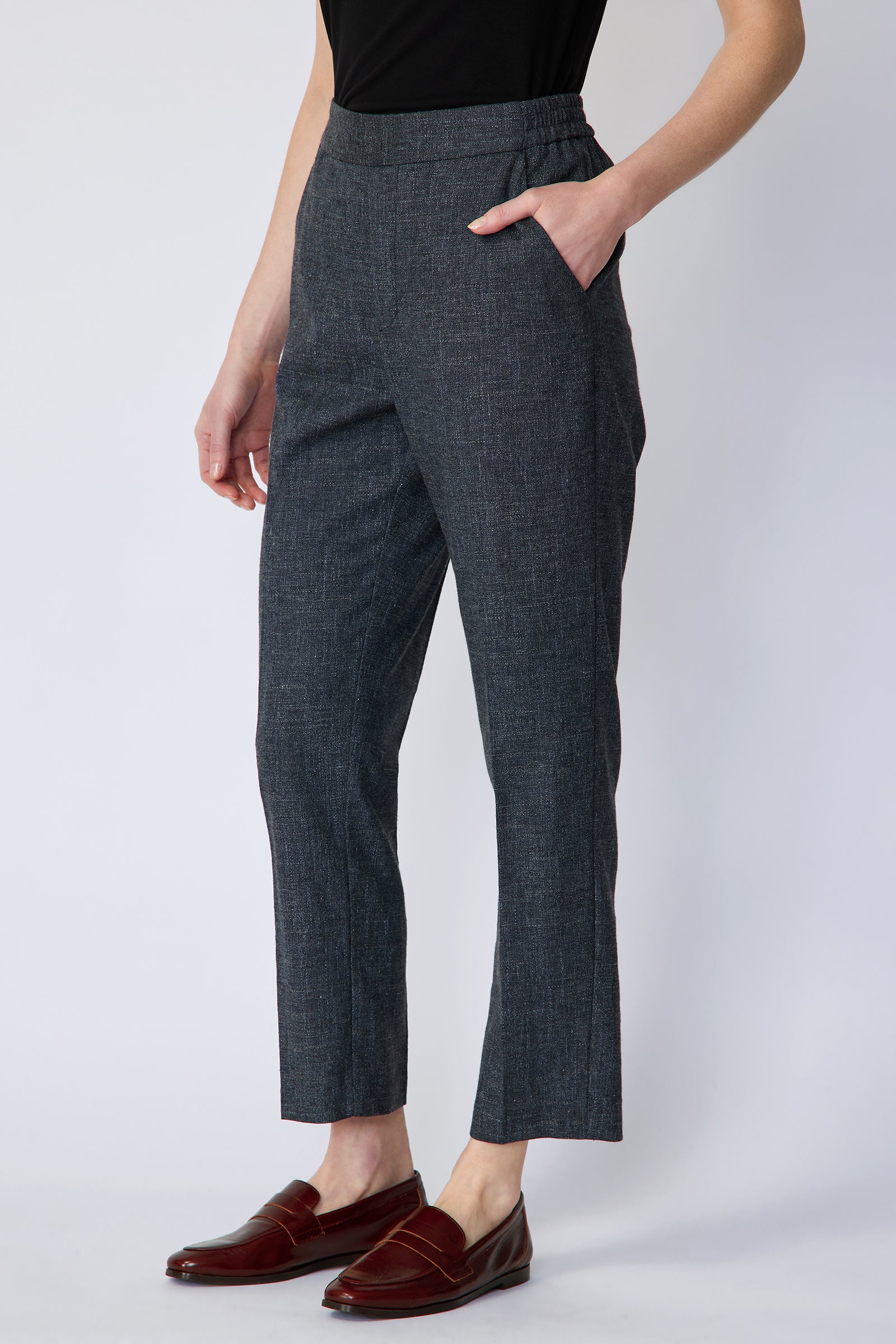 Woman wearing Kal Rieman Martine Trouser in Indigo with brown shoes, hand in pant pocket, arm on side on white background, side view
