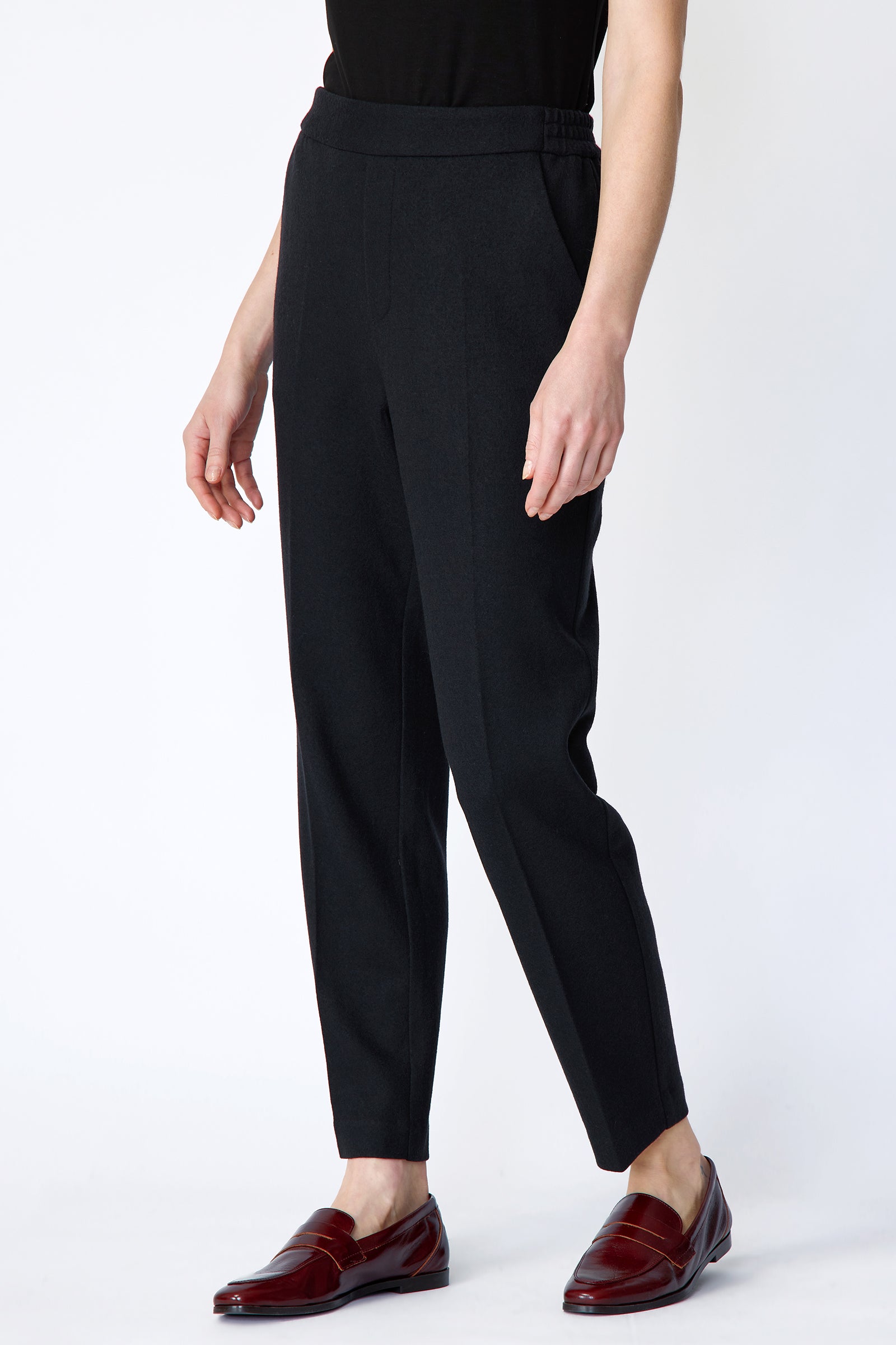 Woman wearing Kal Rieman Martine Trouser in midnight felted jersey with a black tank top and brown shoes, arms on the side, full front view