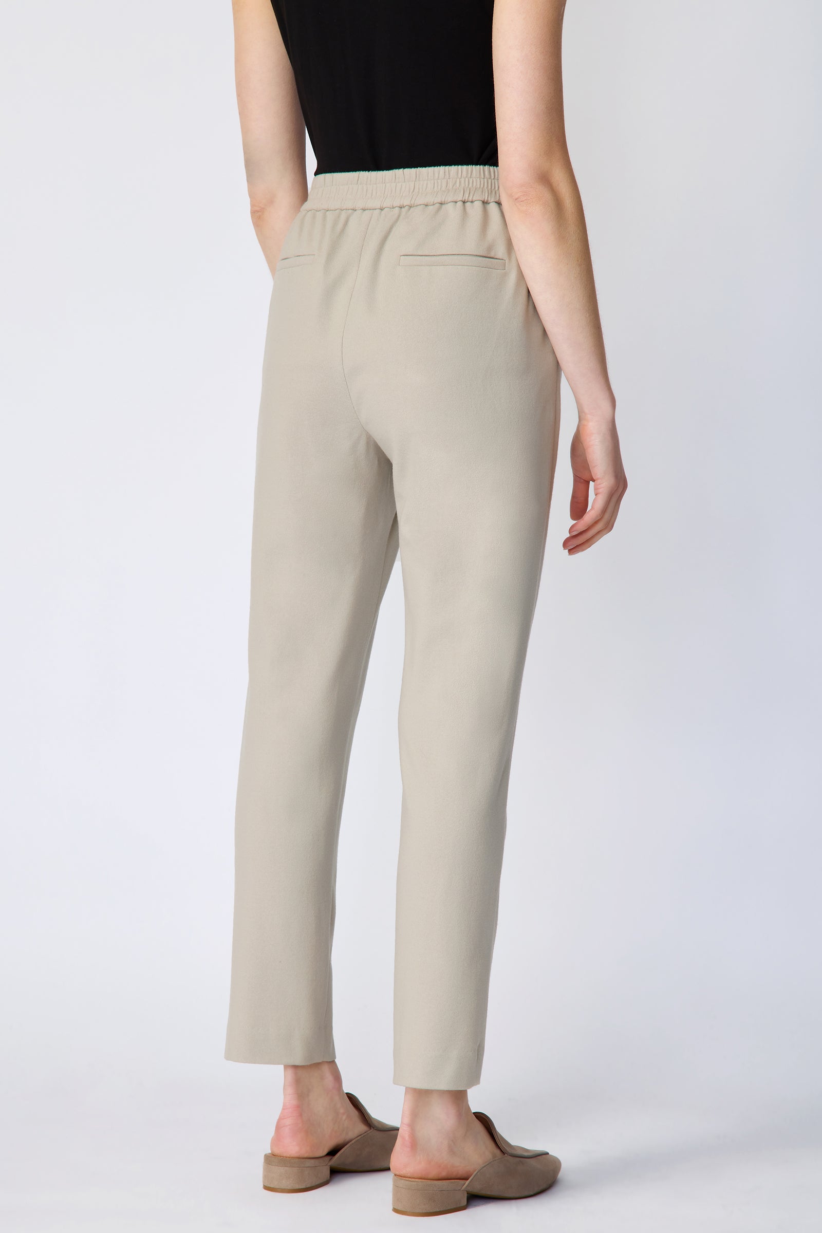 Woman wearing Kal Rieman Martine Trouser in Mink felted jersey with a black tank, beige shoes, arms on the side, close back view