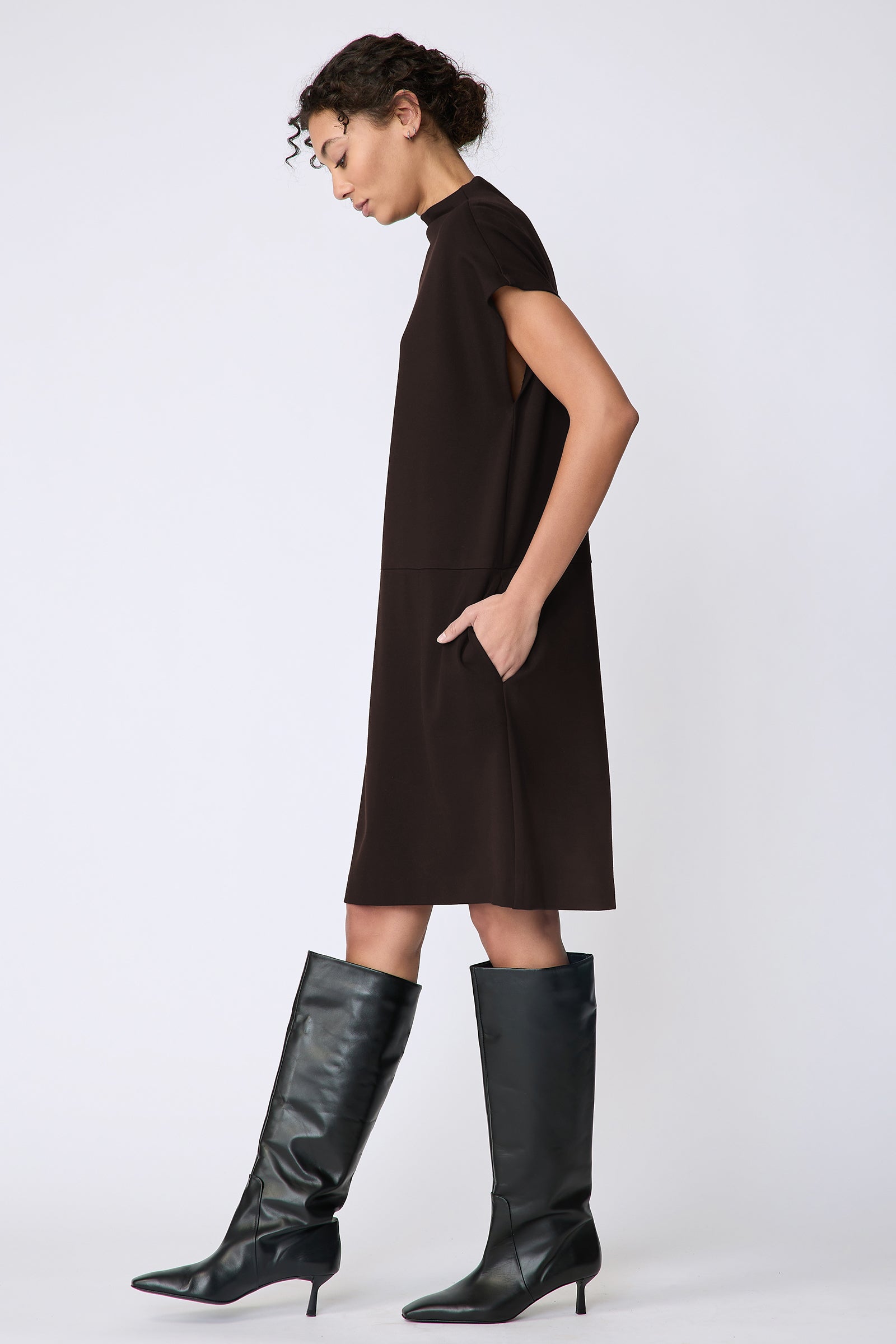 Kal Rieman Maya Funnelneck dress in espresso ponte on model front view walking hands in pockets looking down
