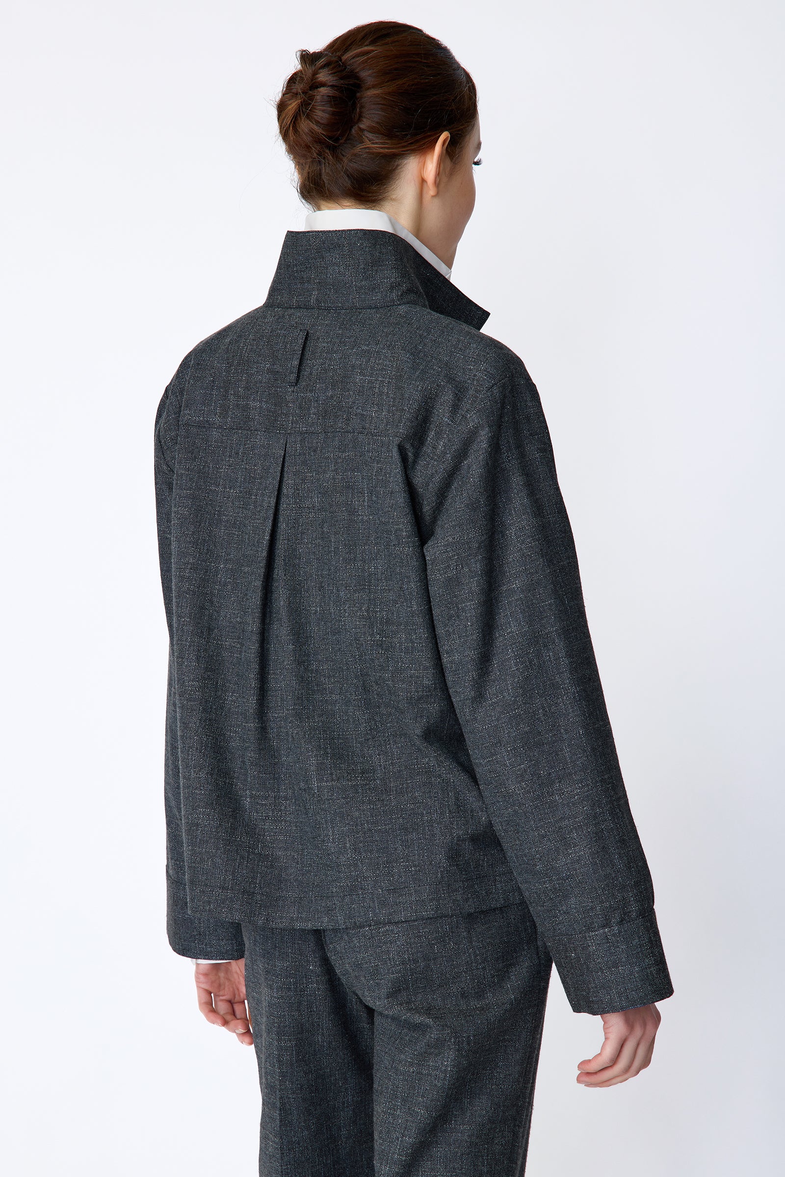 Woman wearing a Kal Rieman Morgan Shirt Jacket in Denim with the Kal Rieman Martine Trouser in Denim on a white background, arms on the side, back view