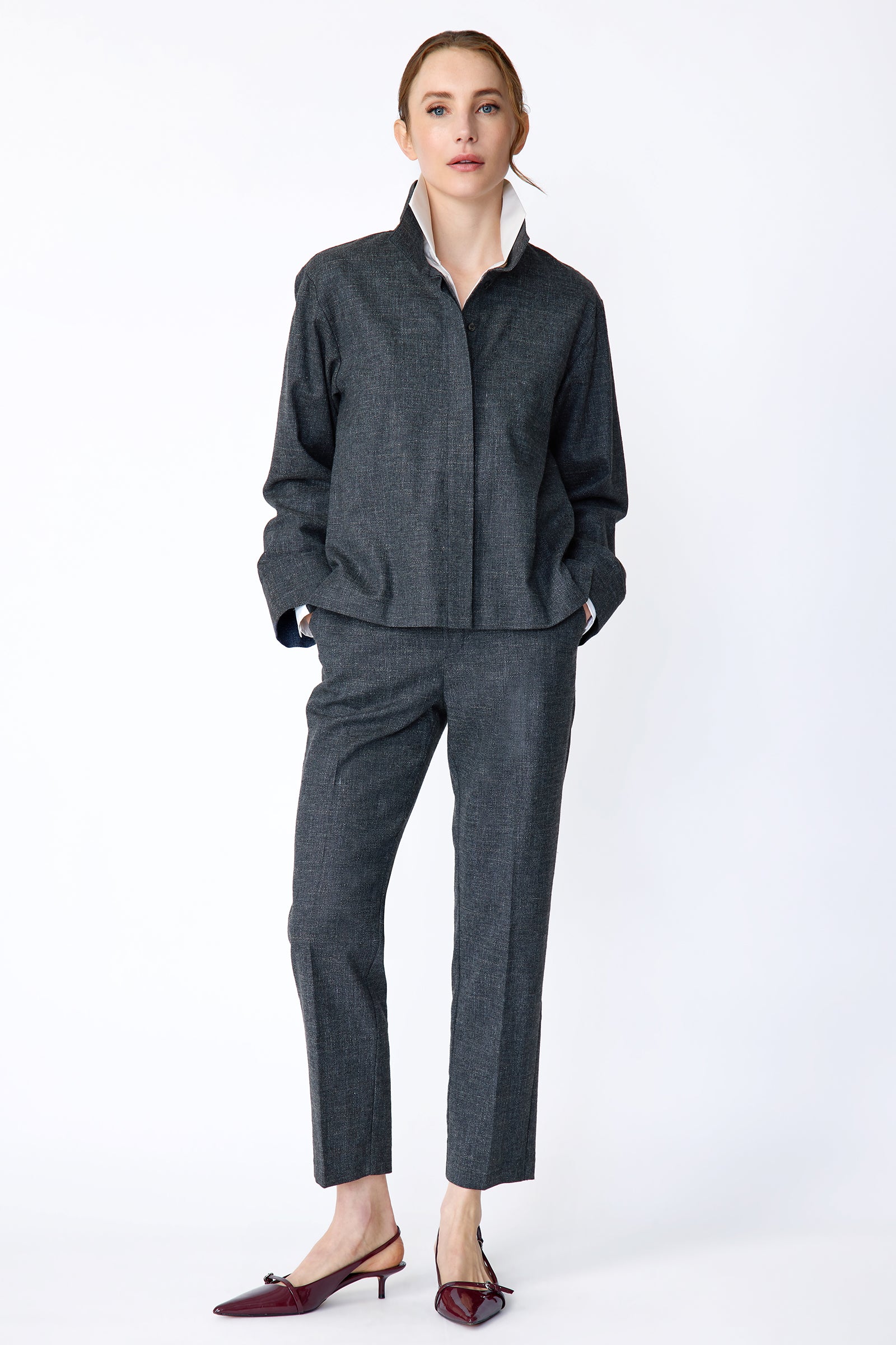 Woman wearing a Kal Rieman Morgan Shirt Jacket in Denim with the Kal Rieman Martine Trouser in Denim on a white background, hands in pant pockets