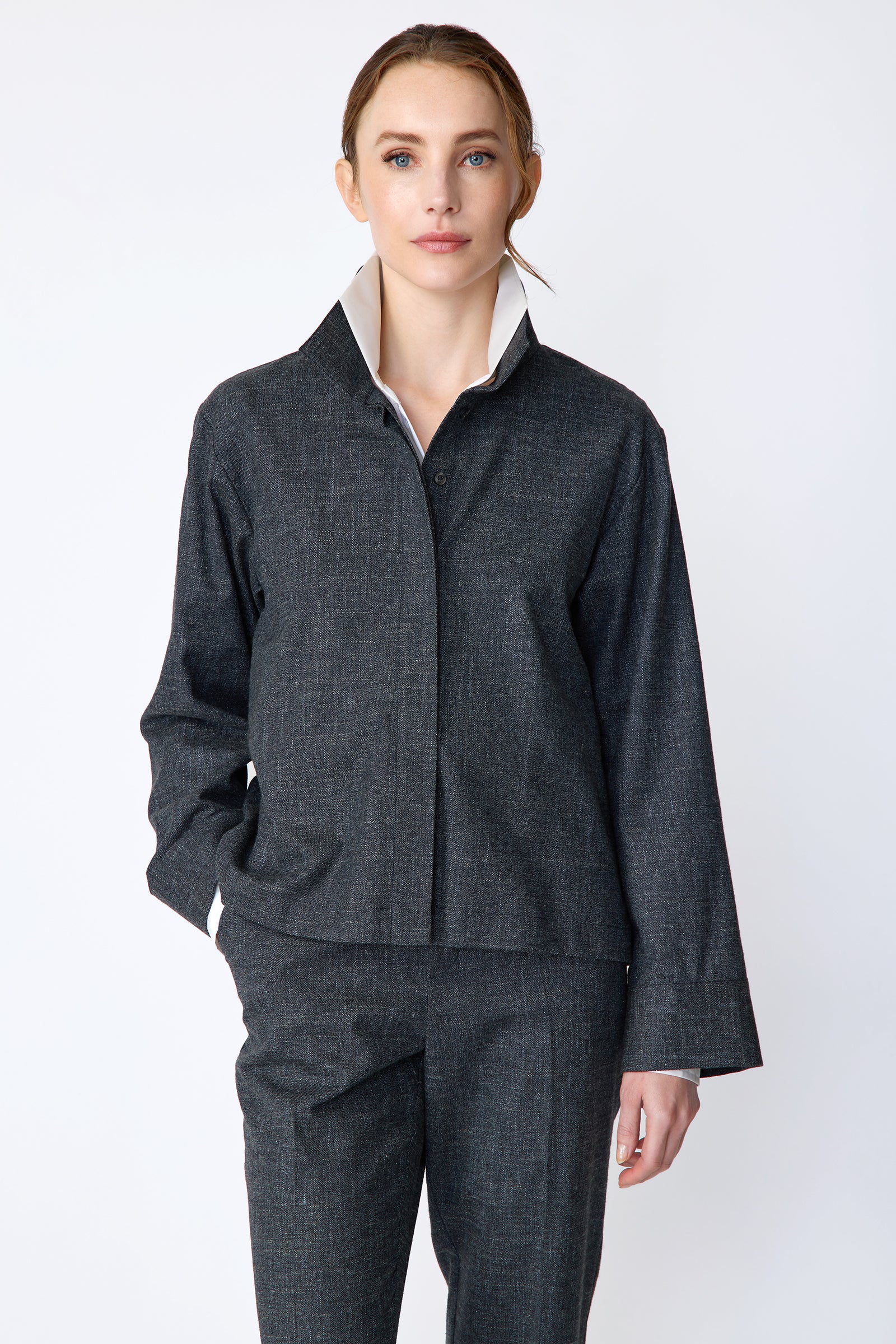 Woman wearing a Kal Rieman Morgan Shirt Jacket in Denim with the Kal Rieman Martine Trouser in Denim on a white background, hand in pant pocket, arm on the side