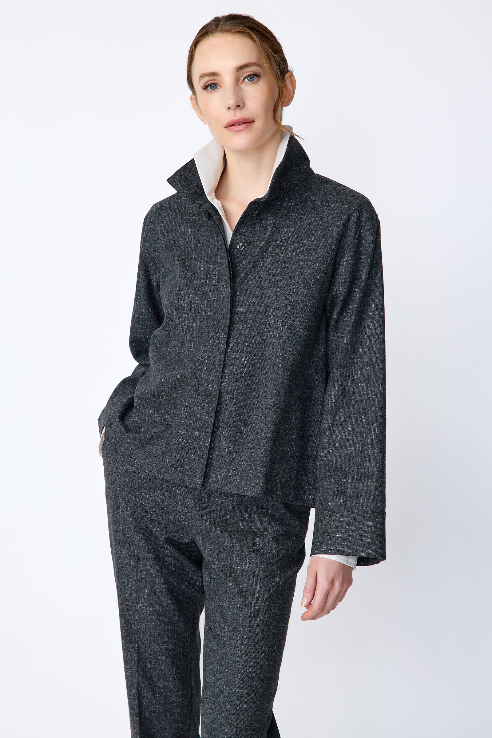 Woman wearing a Kal Rieman Morgan Shirt Jacket in Denim with the Kal Rieman Martine Trouser in Denim on a white background, hand in pant pocket, arm on the side