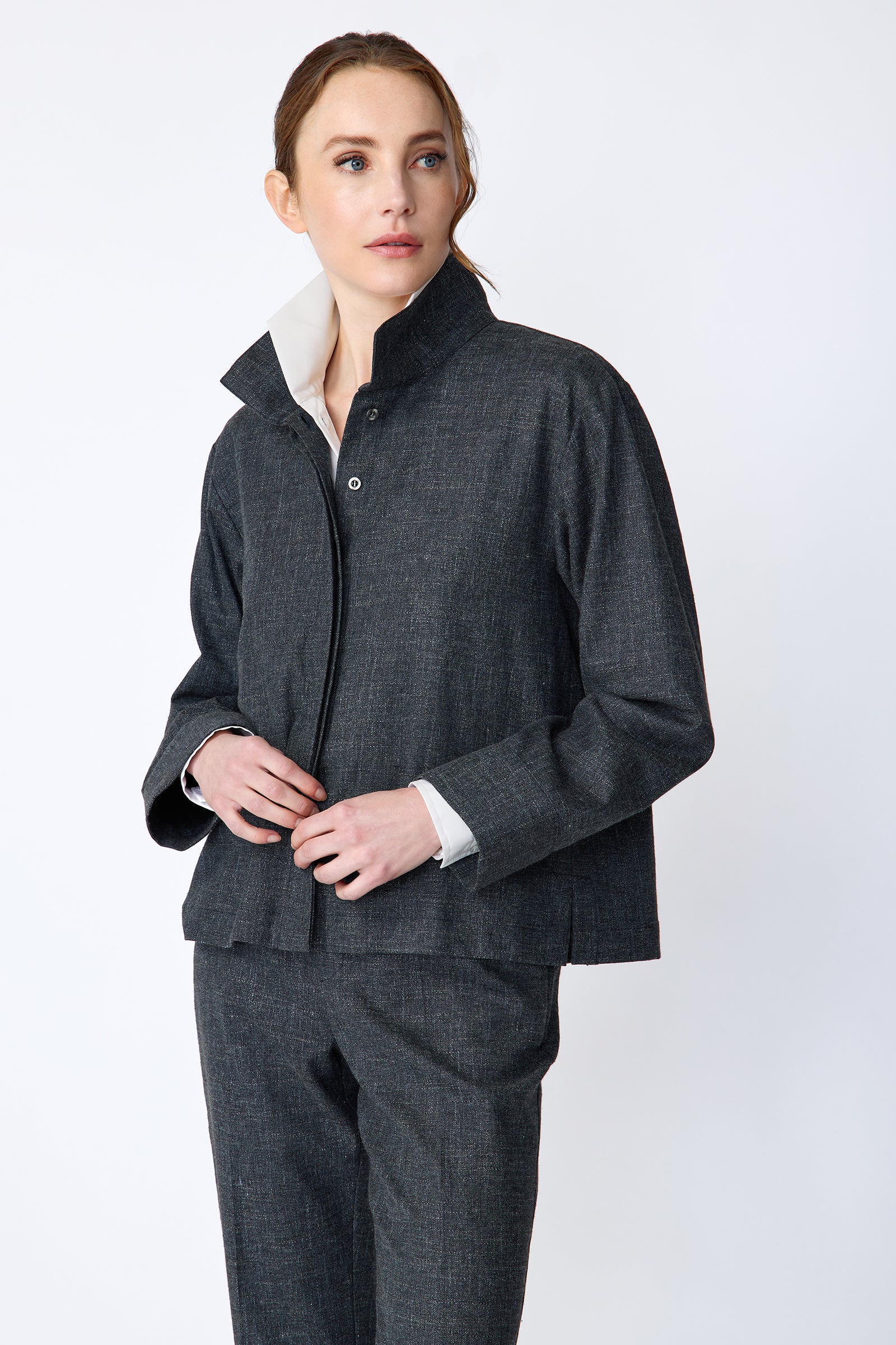 Woman wearing a Kal Rieman Morgan Shirt Jacket in Denim with the Kal Rieman Martine Trouser in Denim on a white background, hands held in front looking sideways