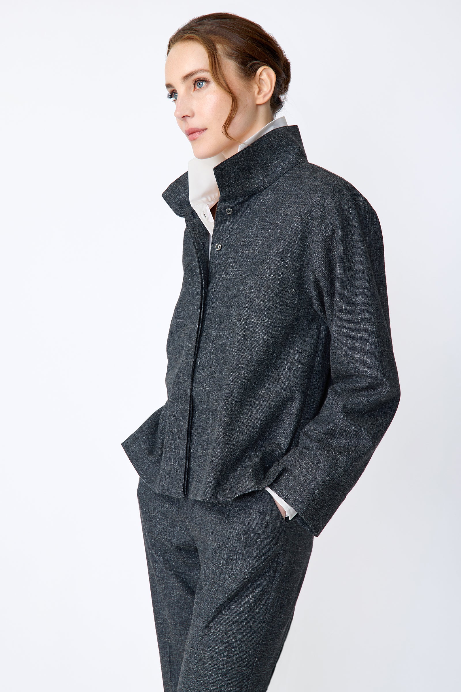 Woman wearing a Kal Rieman Morgan Shirt Jacket in Denim with the Kal Rieman Martine Trouser in Denim on a white background, hands in pant pockets side view