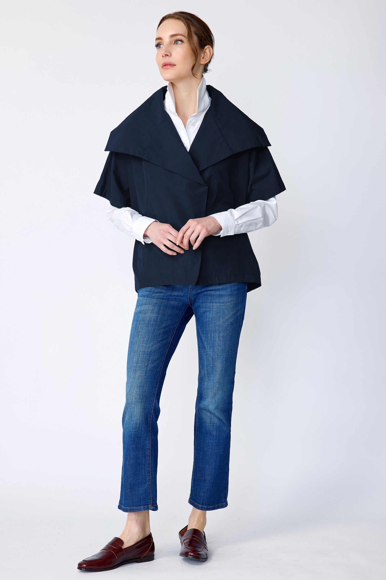 Woman wearing Kal Rieman navy blue Paris jacket, white shirt, and blue jeans on a white background