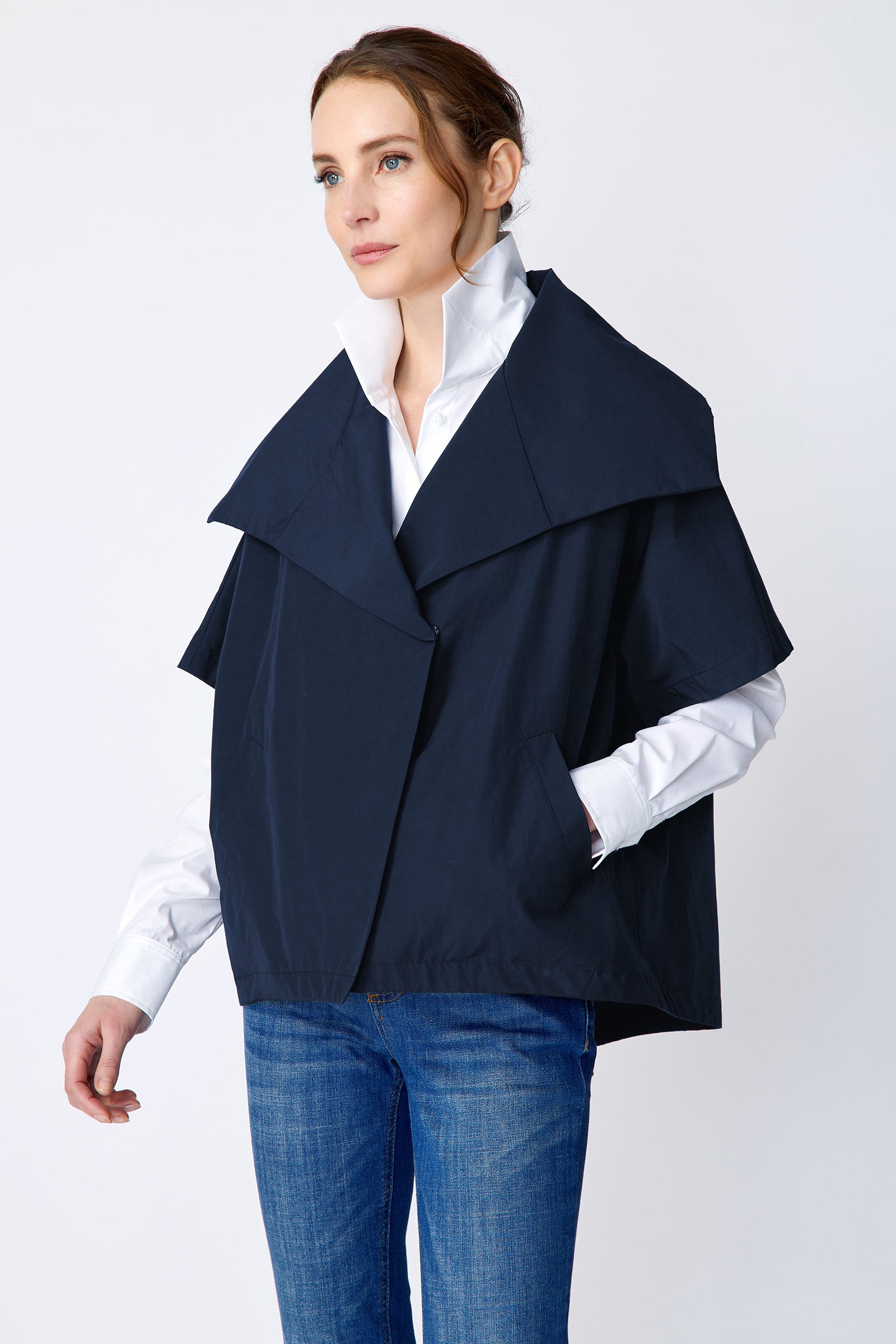 Woman wearing Kal Rieman navy blue Paris jacket, white shirt, and blue jeans on a white background with hand in pocket