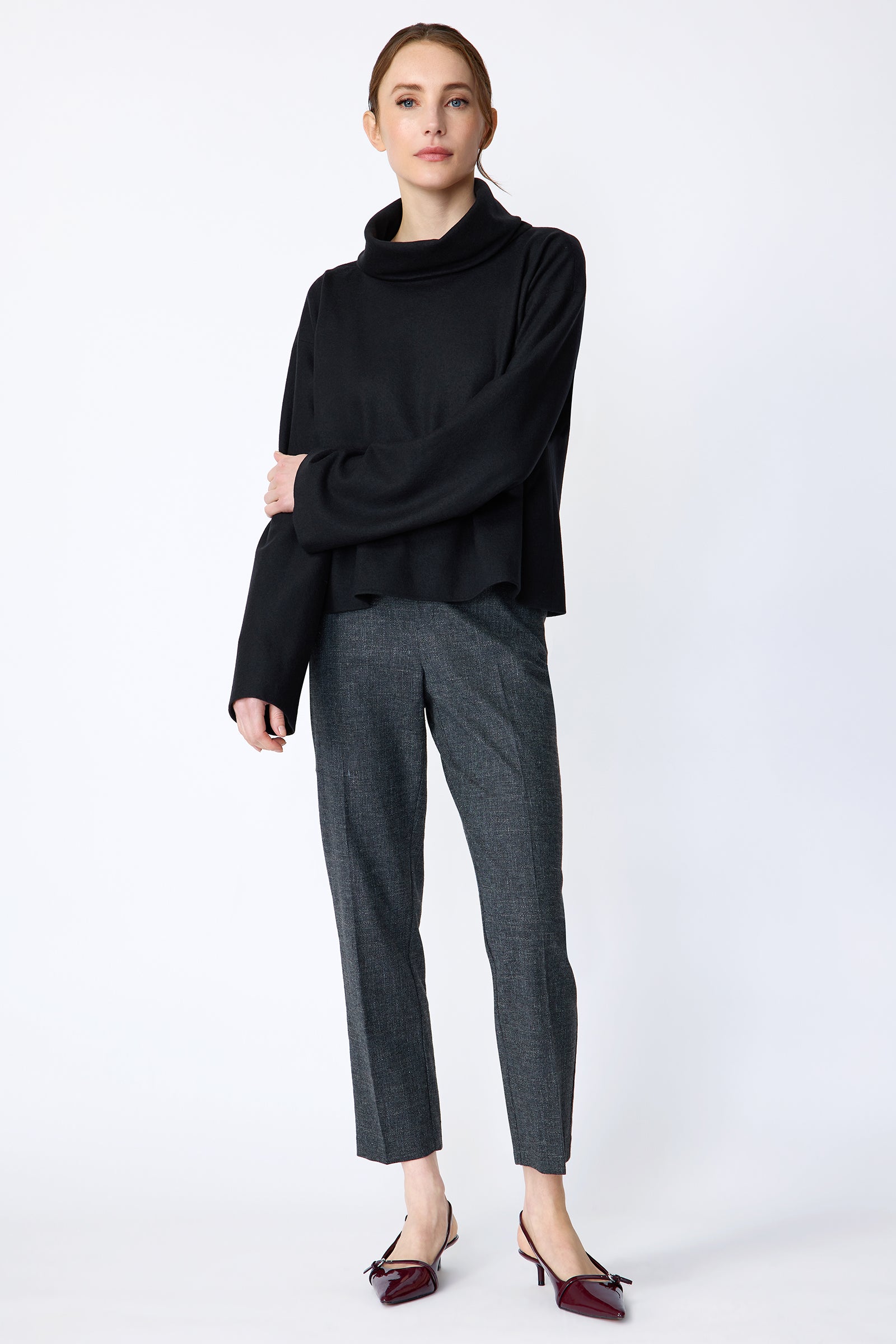 Woman wearing Kal Rieman Polina Tneck Pullover in midnight and Kal Rieman Martine Trouser in Indigo Denim on a white background, arm crossed over, full front view