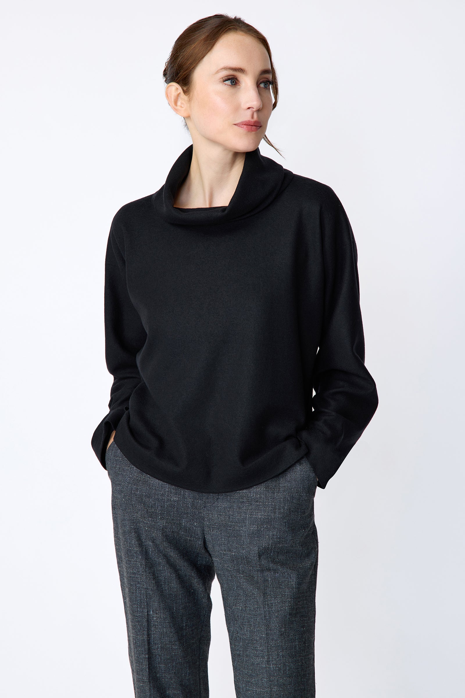 Woman wearing Kal Rieman Polina Tneck Pullover in midnight and Kal Rieman Martine Trouser in Indigo Denim on a white background, hands in pant pockets, close view
