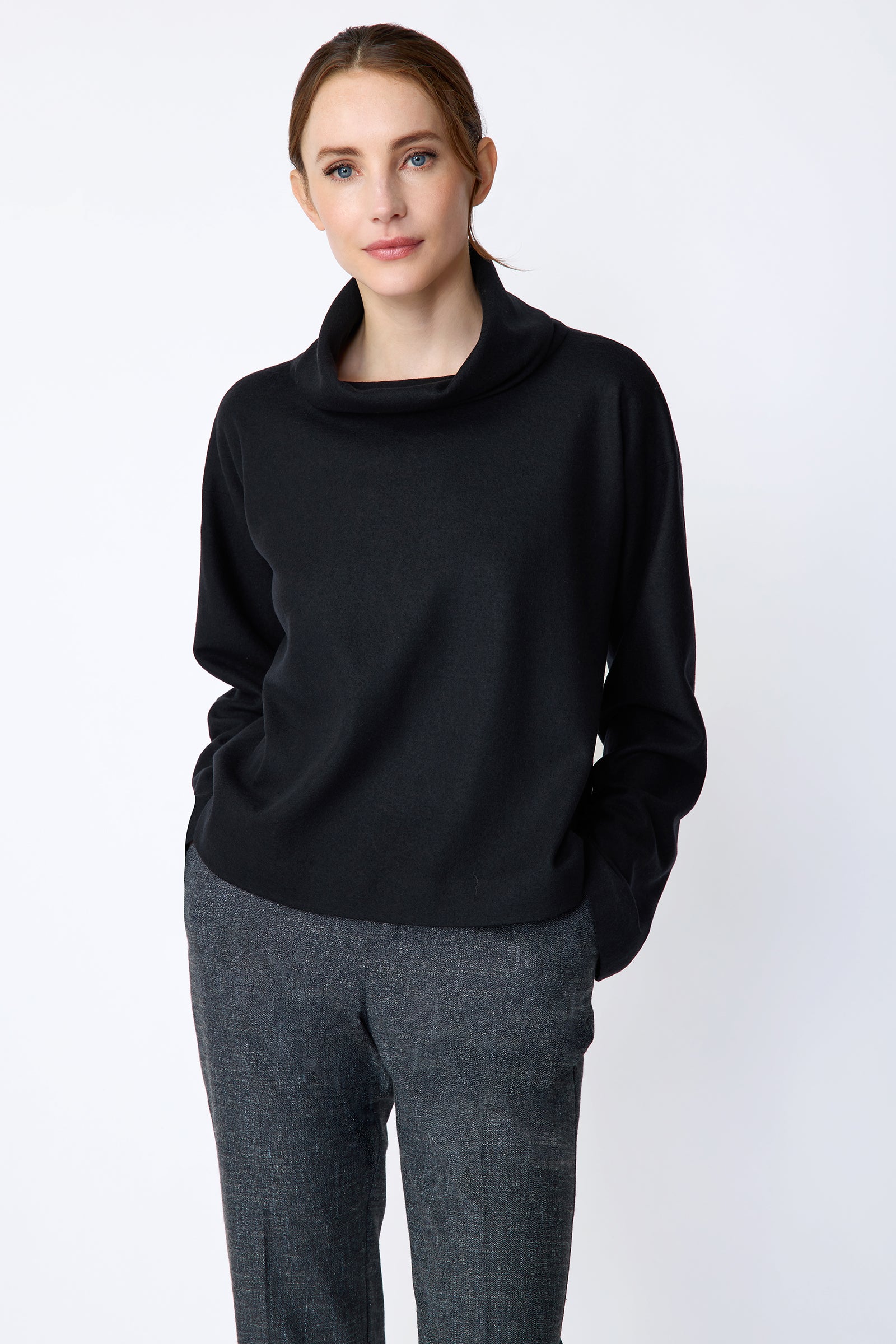 Woman wearing Kal Rieman Polina Tneck Pullover in midnight and Kal Rieman Martine Trouser in Indigo Denim on a white background, hands in pant pockets, close view