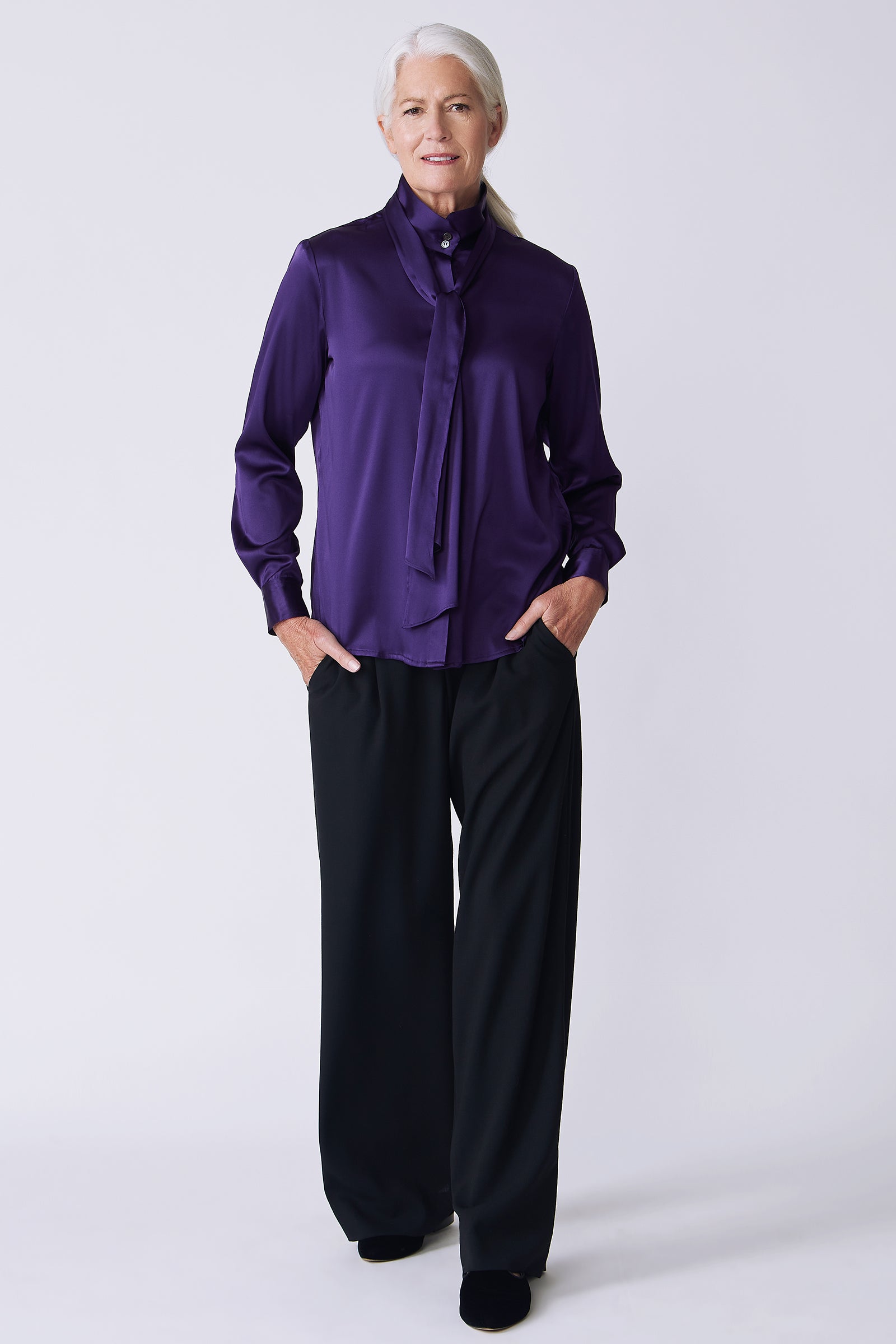 Kal Rieman Regency Silk Blouse in royal purple color charmeuse on model front view hands in pockets walking