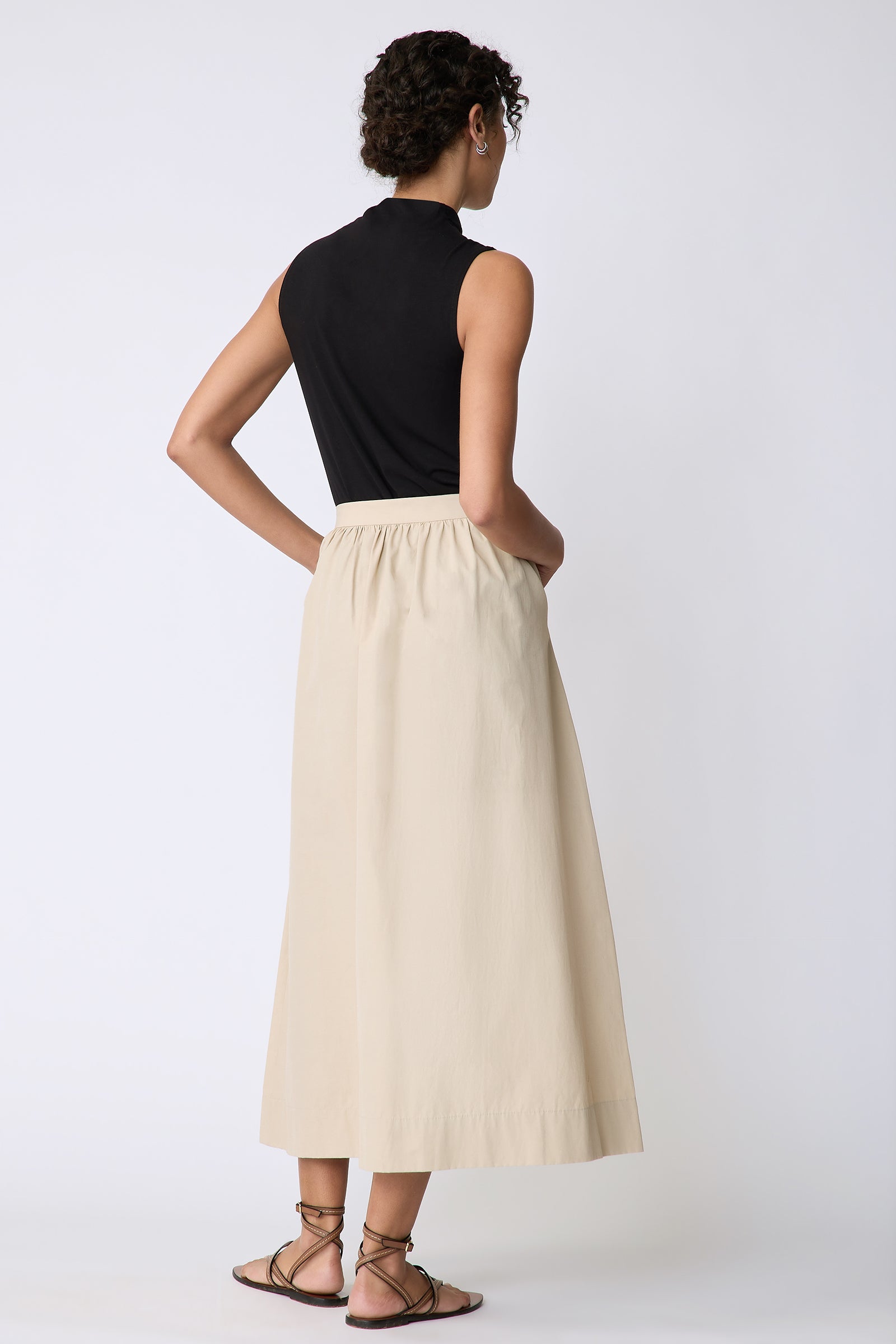 Kal Rieman Sadie Skirt in Italian Broadcloth color sand on model back  view hands in pockets