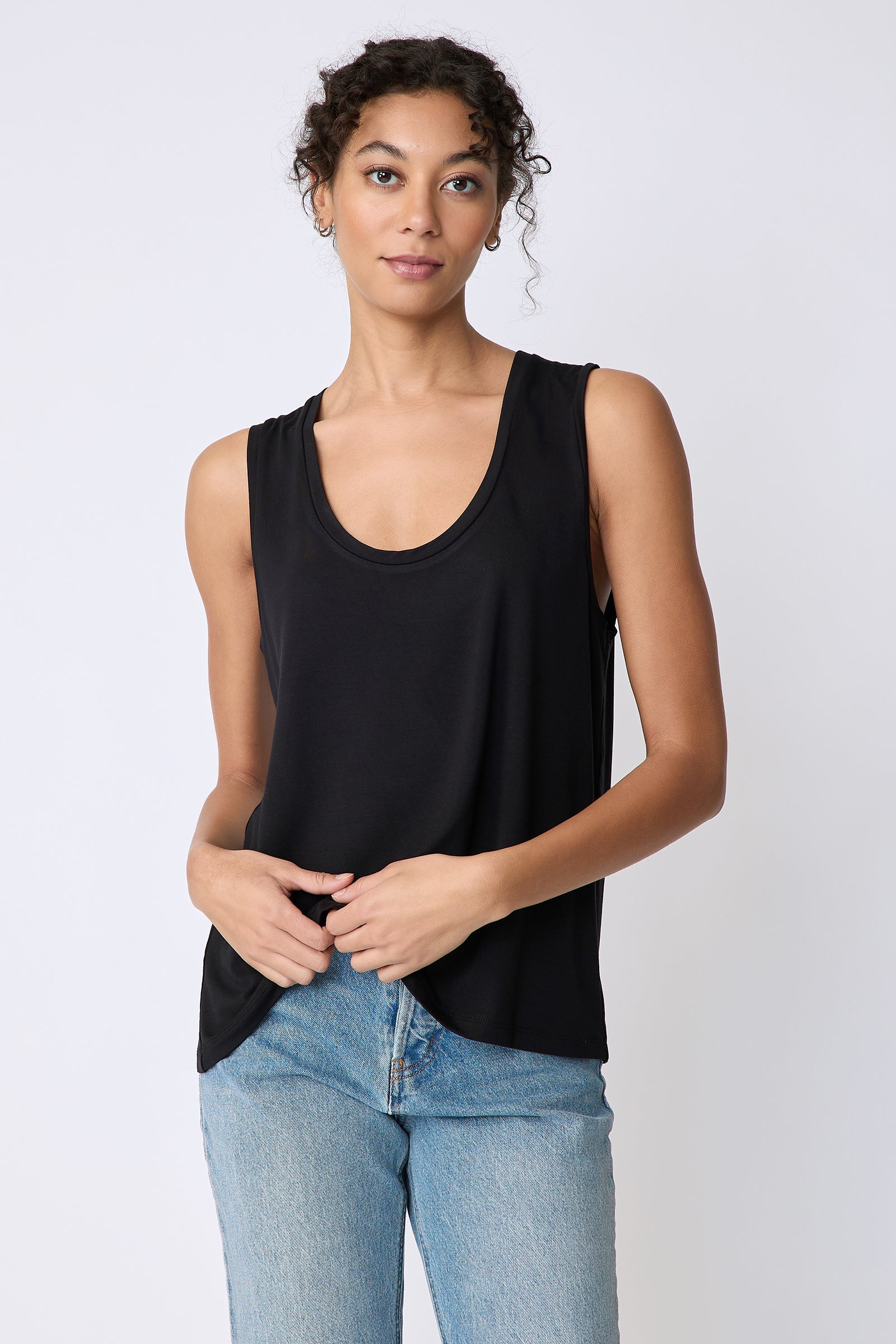 Kal Rieman Sandra Scoop Tank in black bamboo jersey on model front view holding hem