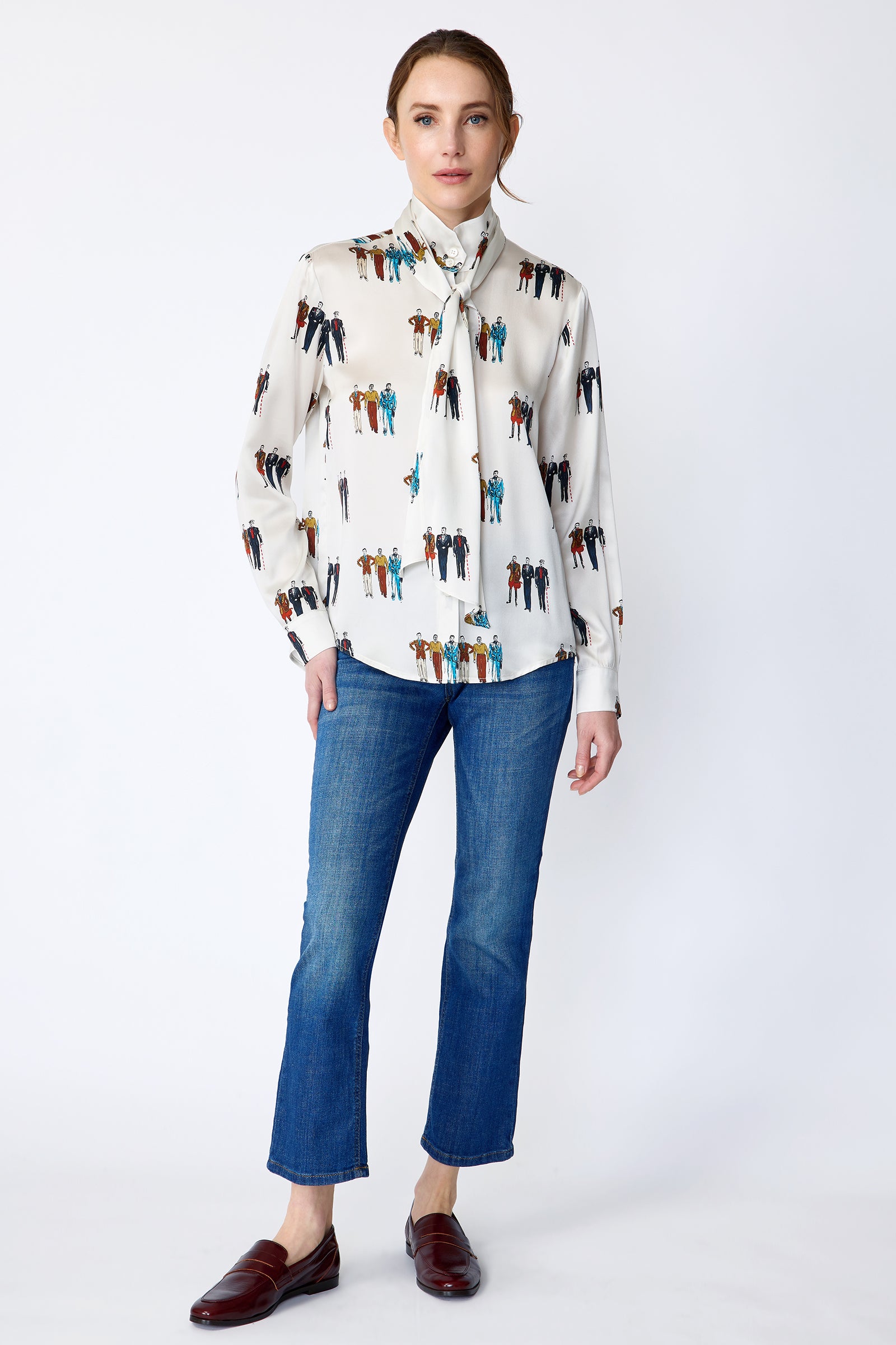 Woman wearing Kal Rieman Silk Regency Blouse in Dandy Print with blue jeans on a white background, arms on sides