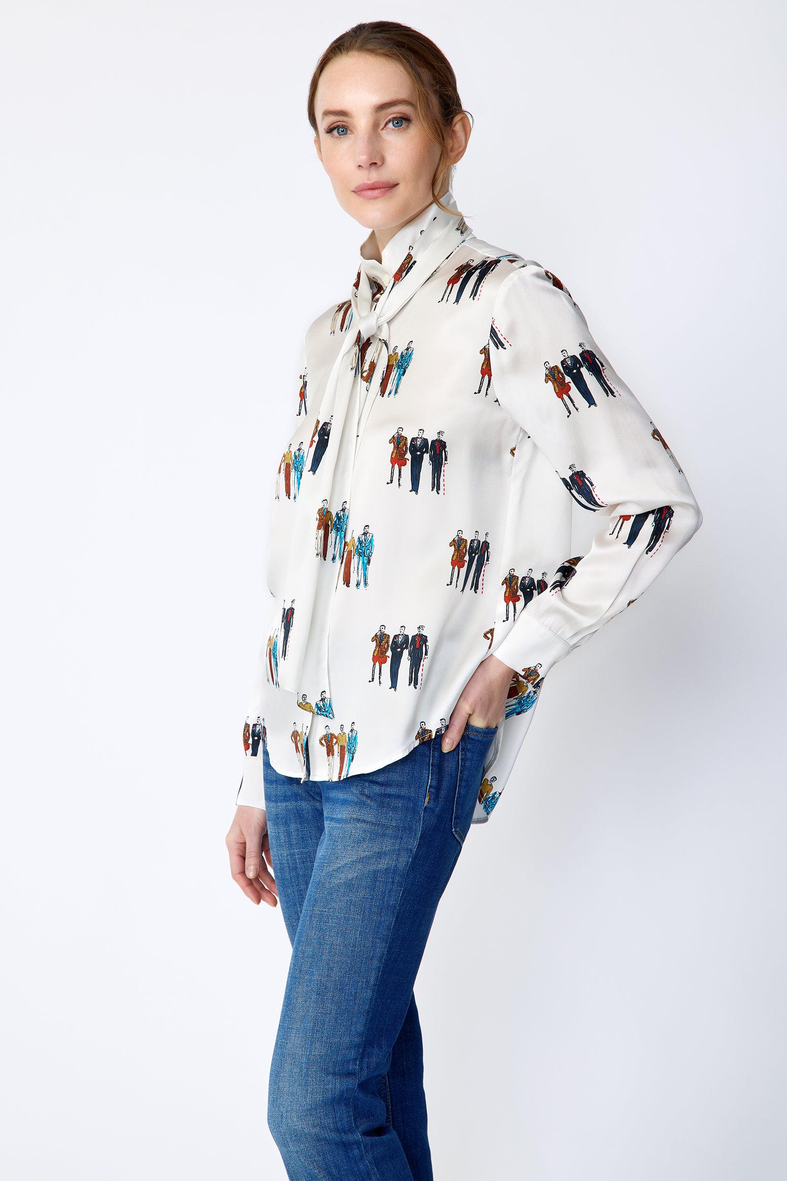 Woman wearing Kal Rieman Silk Regency Blouse in Dandy Print with blue jeans on a white background, arm in back pocket side view