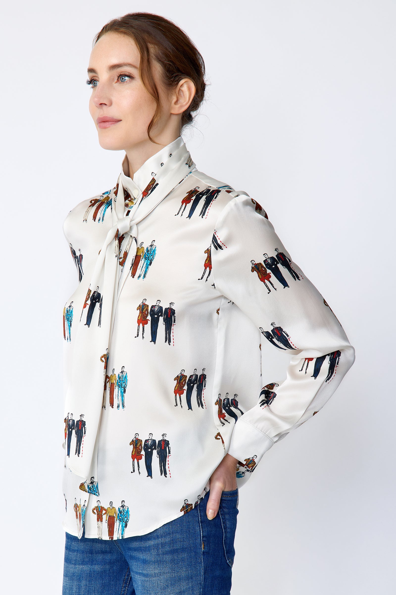 Woman wearing Kal Rieman Silk Regency Blouse in Dandy Print with blue jeans on a white background, arms in pocket, side view