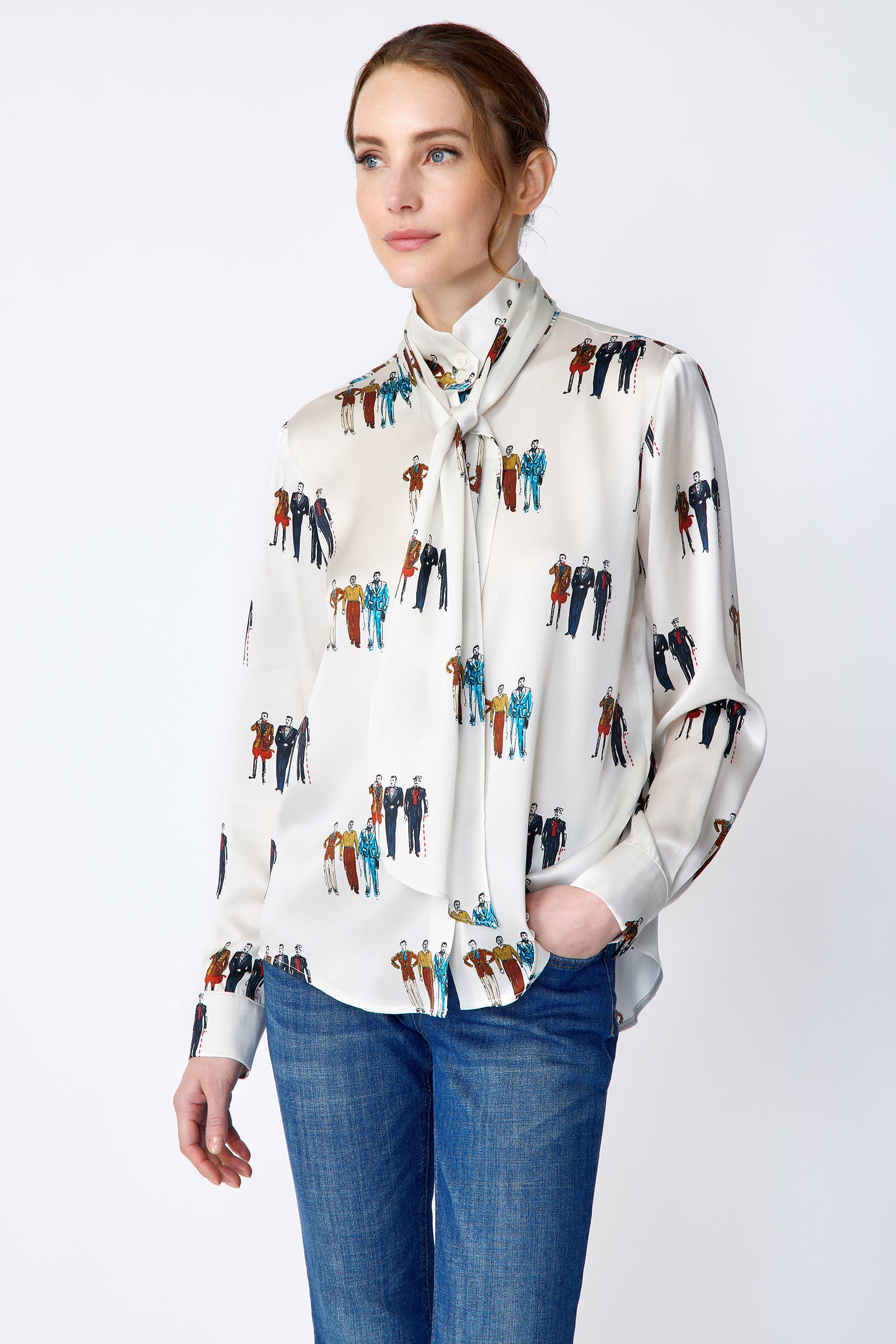 Woman wearing Kal Rieman Silk Regency Blouse in Dandy Print with blue jeans on a white background, pant in jean pocket, arm on side looking side ways