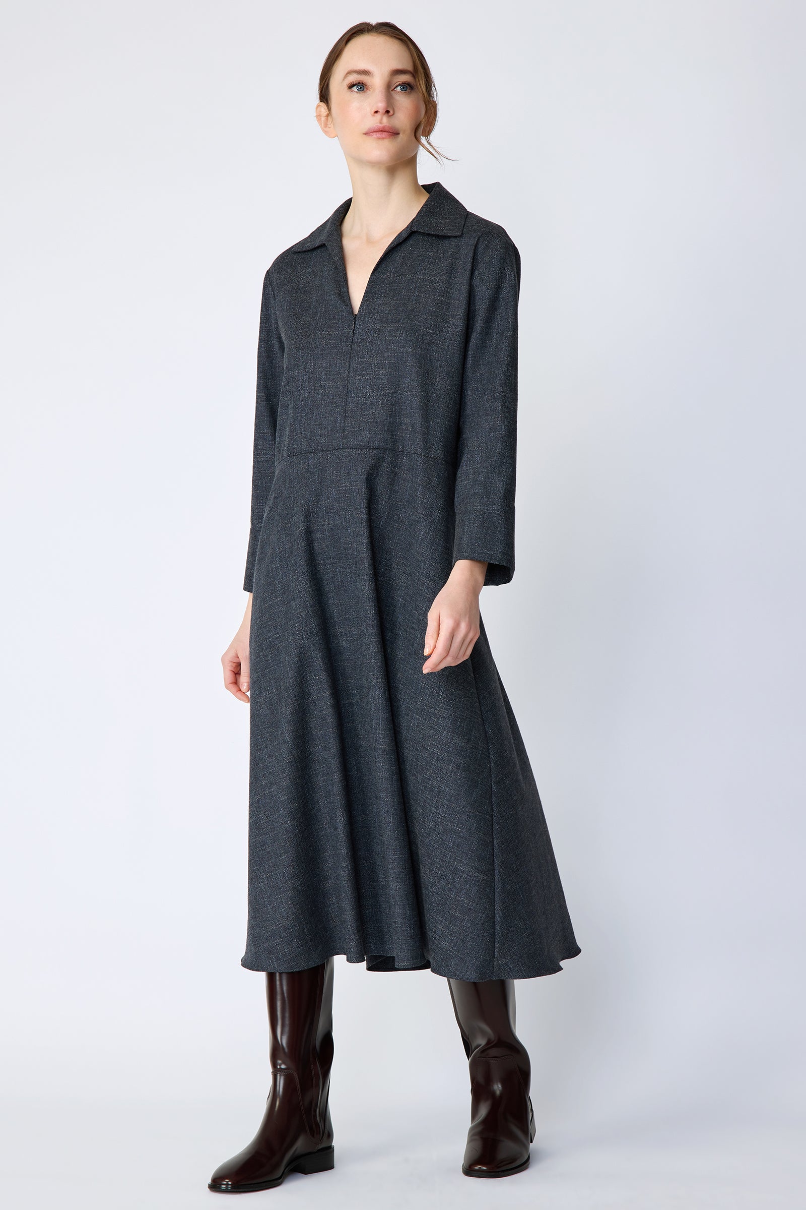 Woman wearing Kal Rieman Sydney Dress in Indigo Denim Wool with brown boots, arms on the side, looking sideways, full front view