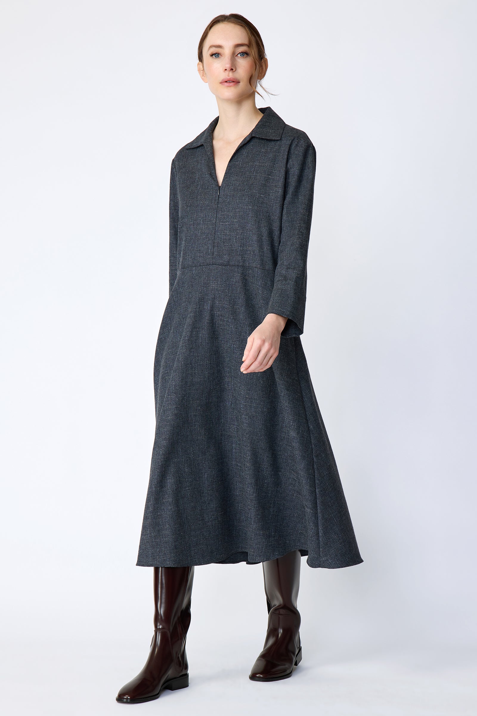 Woman wearing Kal Rieman Sydney Dress in Indigo Denim Wool with brown boots, arms on the side, full front view, walking