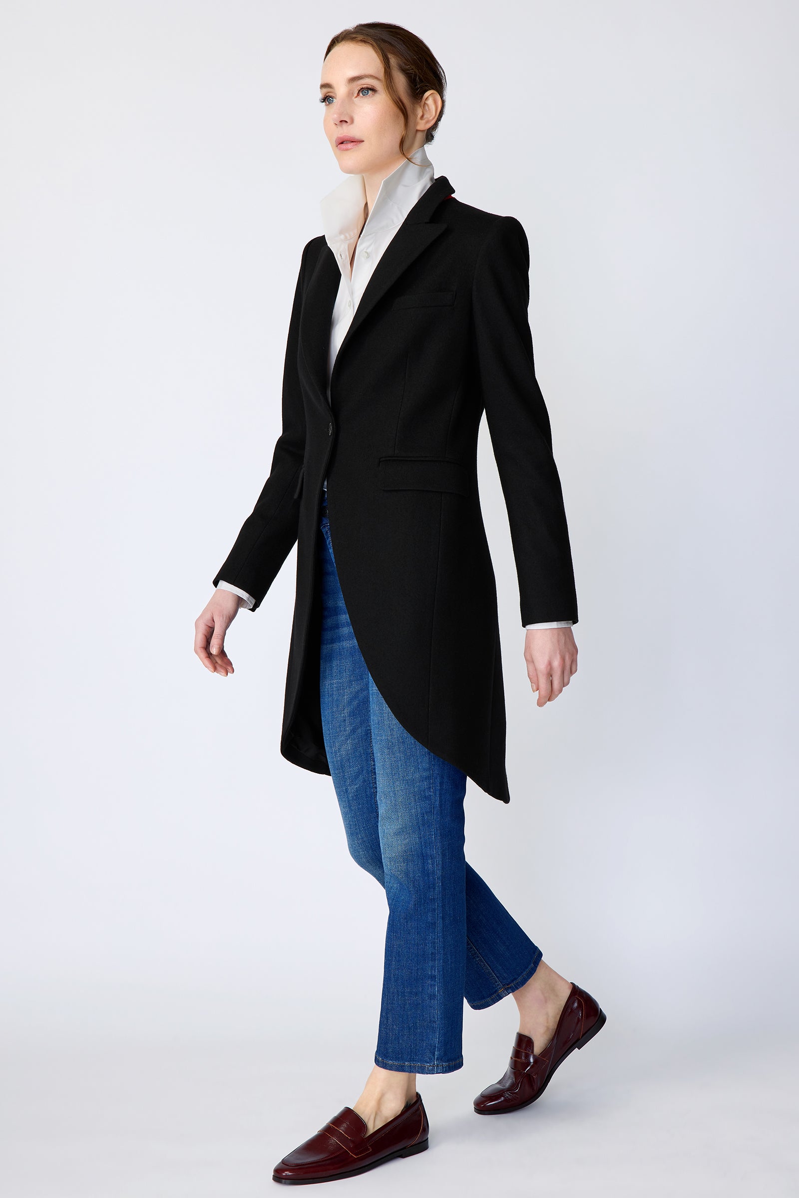 Woman wearing Kal Rieman Tailored Tux Blazer in Black, Collar unfolded, with blue jeans and brown shoes, arms on the side, walking
