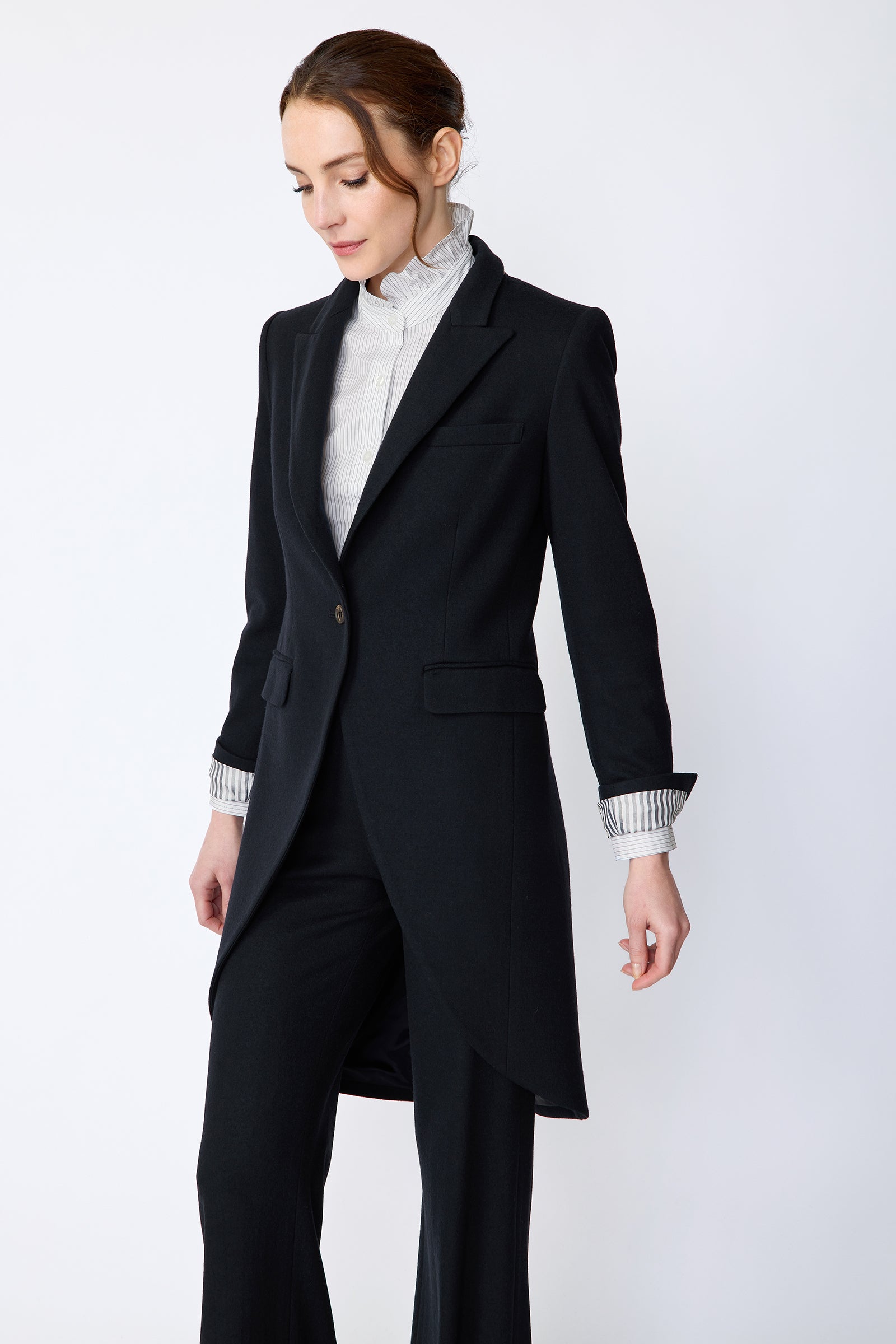 Woman wearing Kal Rieman Tailored Tux Blazer in Midnight over Kal Rieman Amy Ruffle Collar shirt with Kal Rieman felted Jersey Wide Leg pants in midnight, arms on the side, looking down