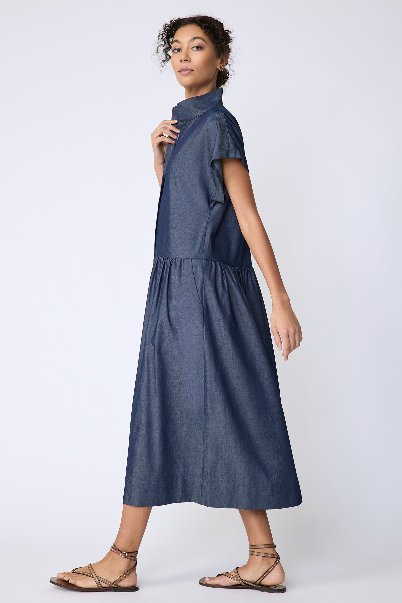 Kal Rieman Tanya Dress in Indigo light weight denim on model side view walking holding collar