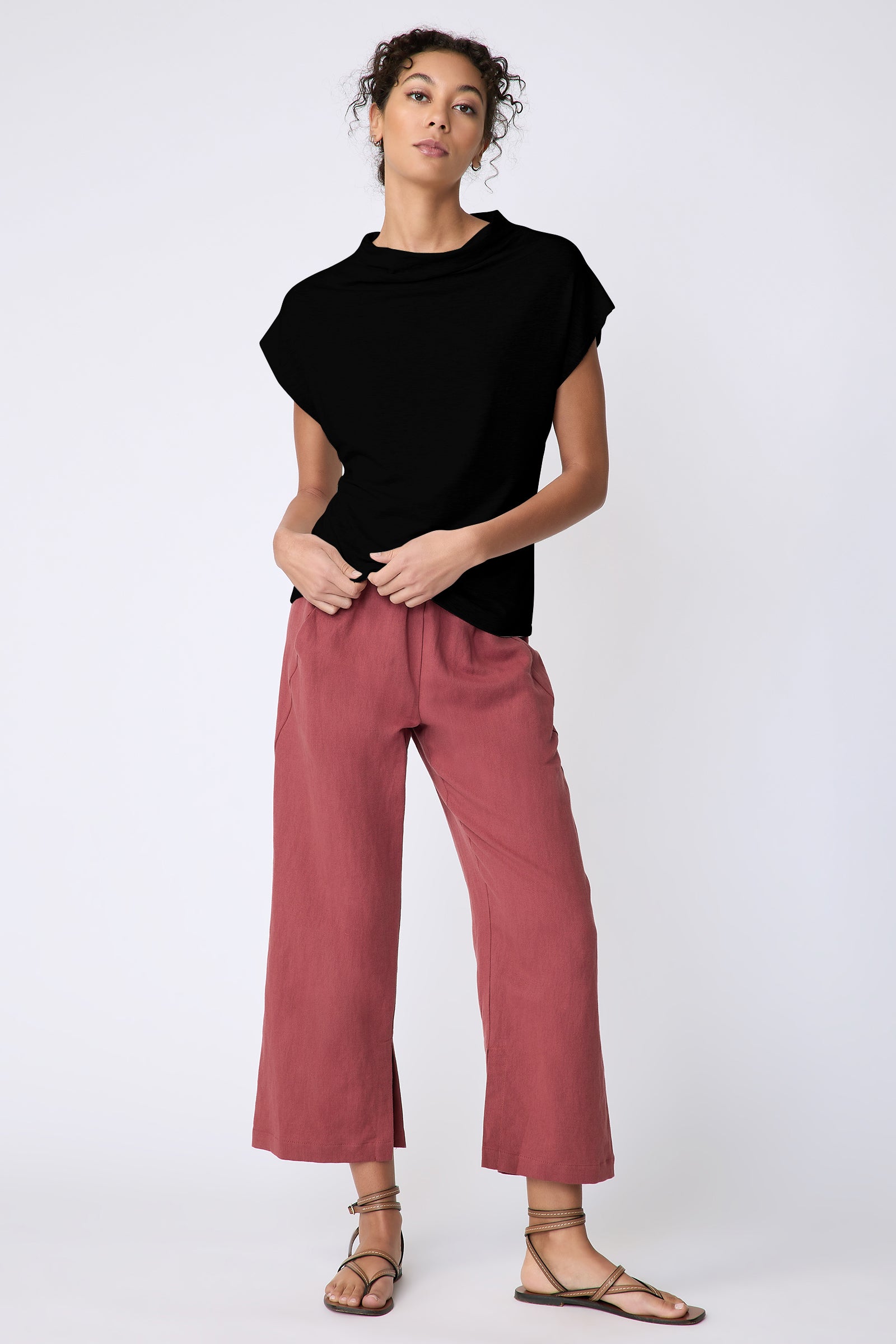Kal Rieman Uma Funnelneck Tee in Black on model front view full length holding hem of shirt