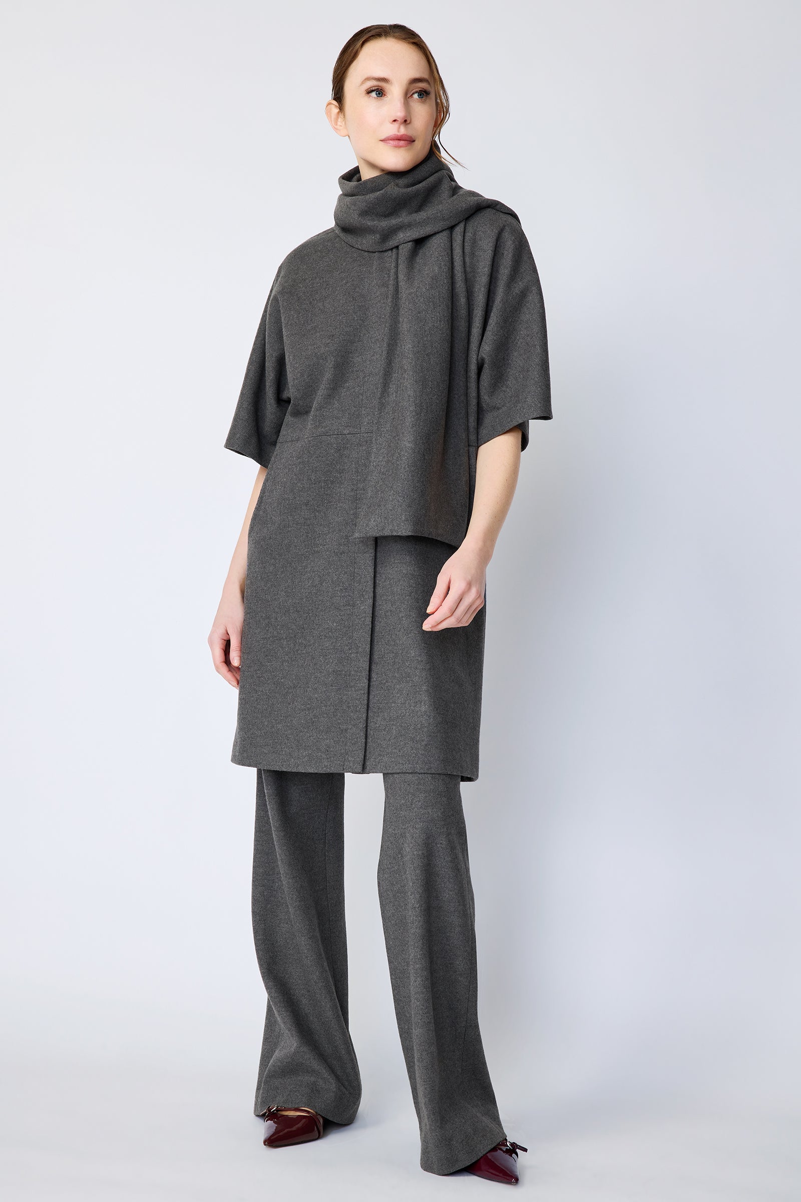 Woman wearing Kal Rieman York Cardigan  in Grey Italian Felted Jersey with Kal Rieman Felted Jersey Wide Leg pants in Grey italian Felted Jersey and burgundy shoes, arms on the side, full front view,  looking sideways