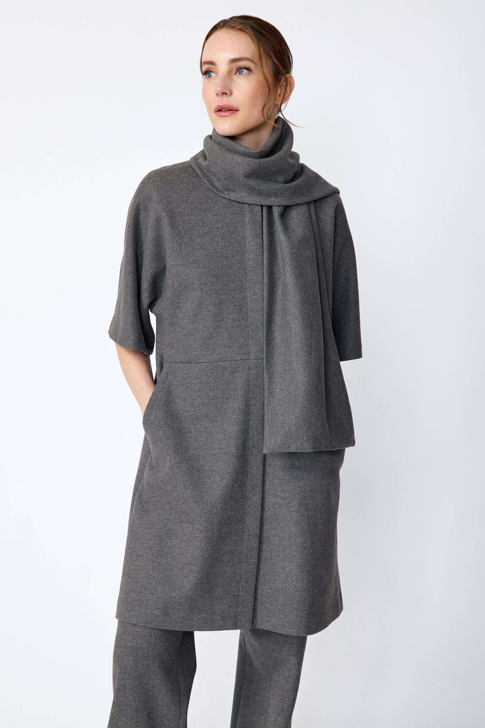 Woman wearing Kal Rieman York Cardigan  in Grey Italian Felted Jersey with Kal Rieman Felted Jersey Wide Leg pants in Grey italian Felted Jersey, arm on the side, hand in pocket, close front view,  looking sideways