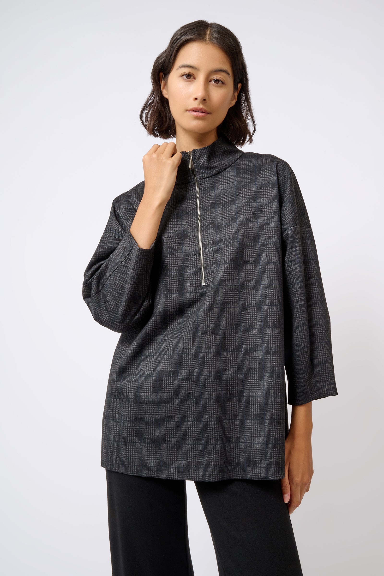Kal Rieman Zip Mock Top in Black Plaid on Model with Hand Up Front View Cropped