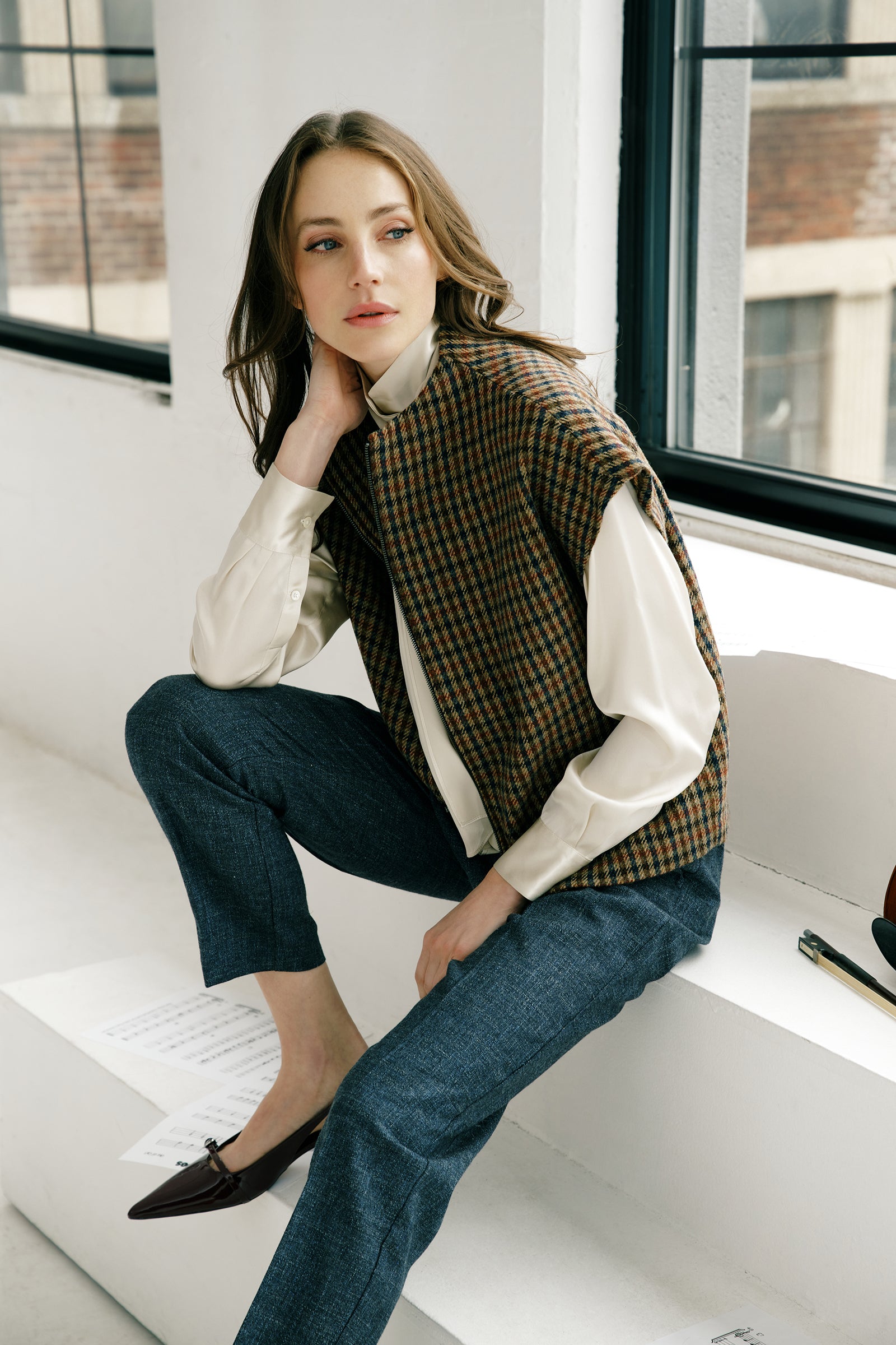 Woman wearing Kal Rieman Bruna Zip Vest in Heritage Check over a Kal Rieman Silk Regency Blouse in Oyster with a white background, hands holding zip, close view