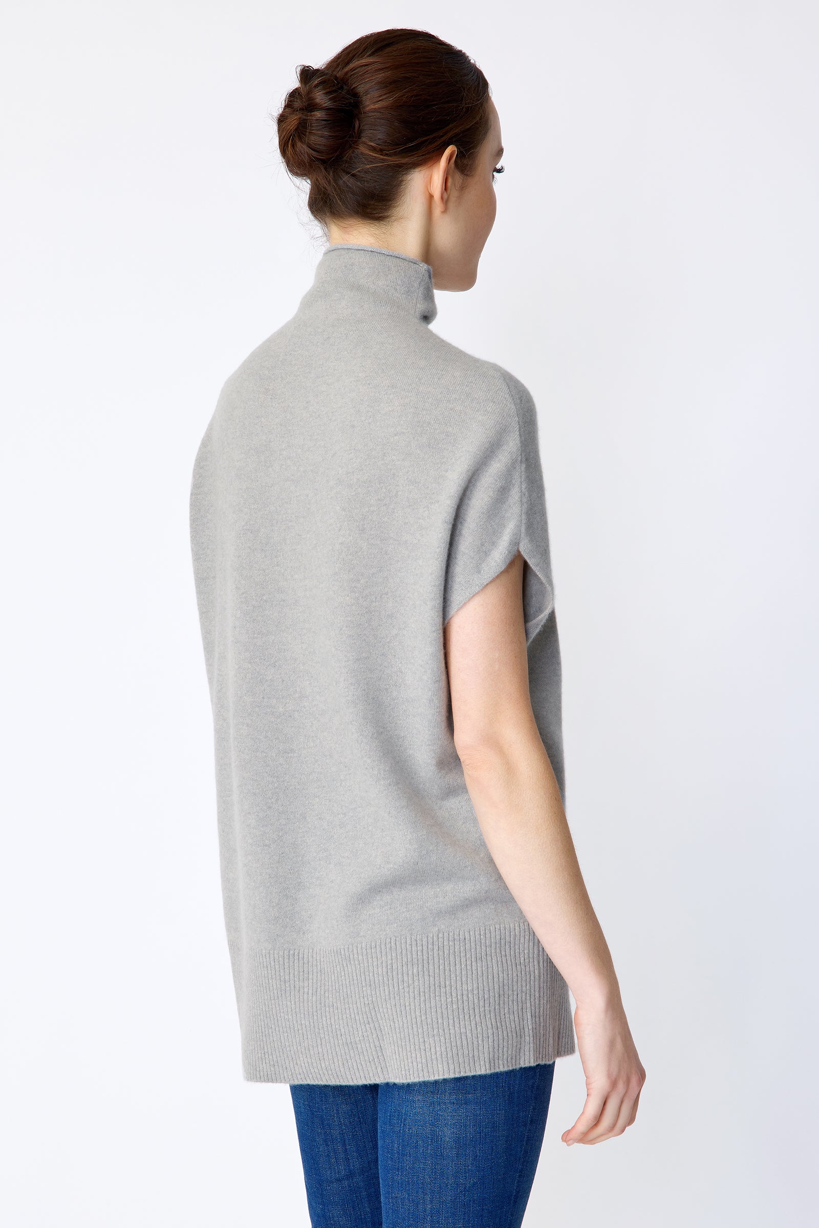 Woman wearing Kal Rieman Cashmere Funnelneck in Heather gray, blue jeans, and brown shoes on a white background arms crossed in front