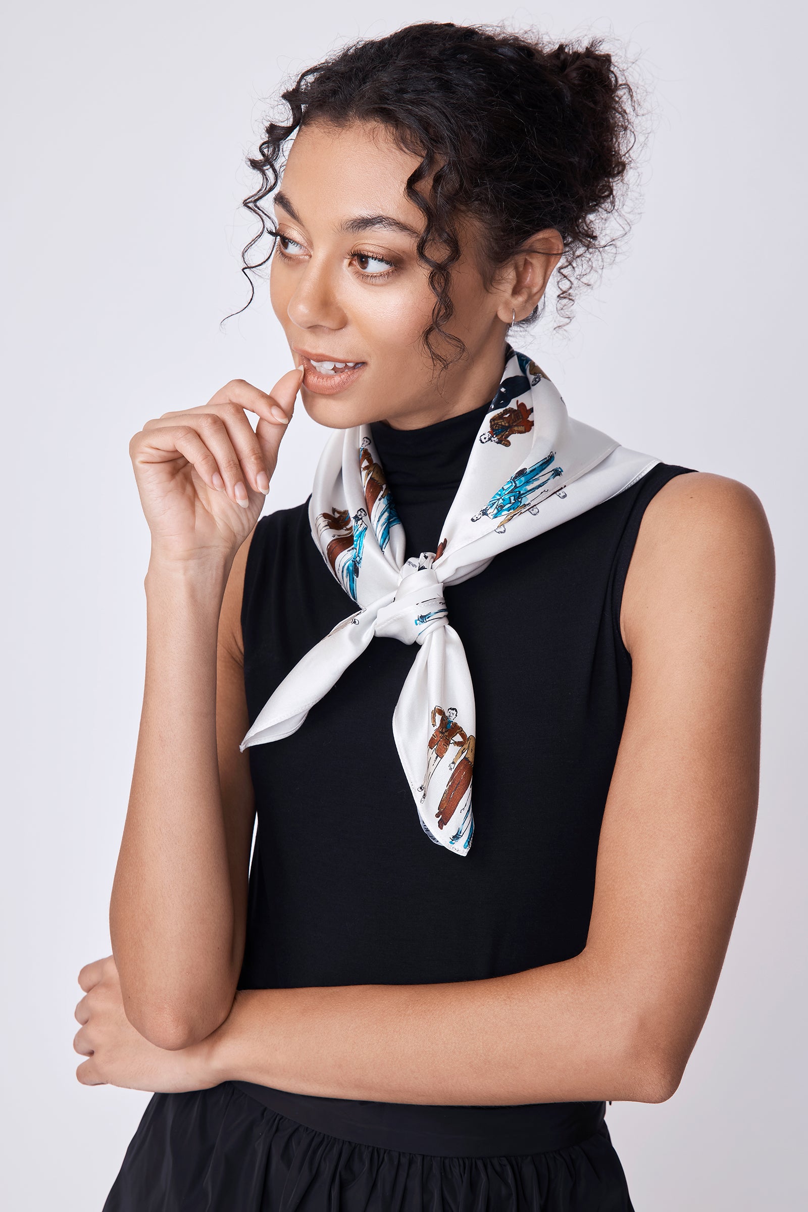 Woman wearing a black sleeveless top with a dandy print scarf around her neck against a white background