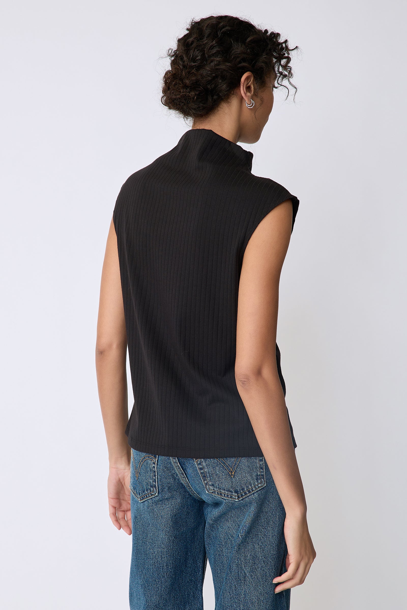 Kal Rieman Eva Funnelneck top in black rib knit on model front view arms crossed