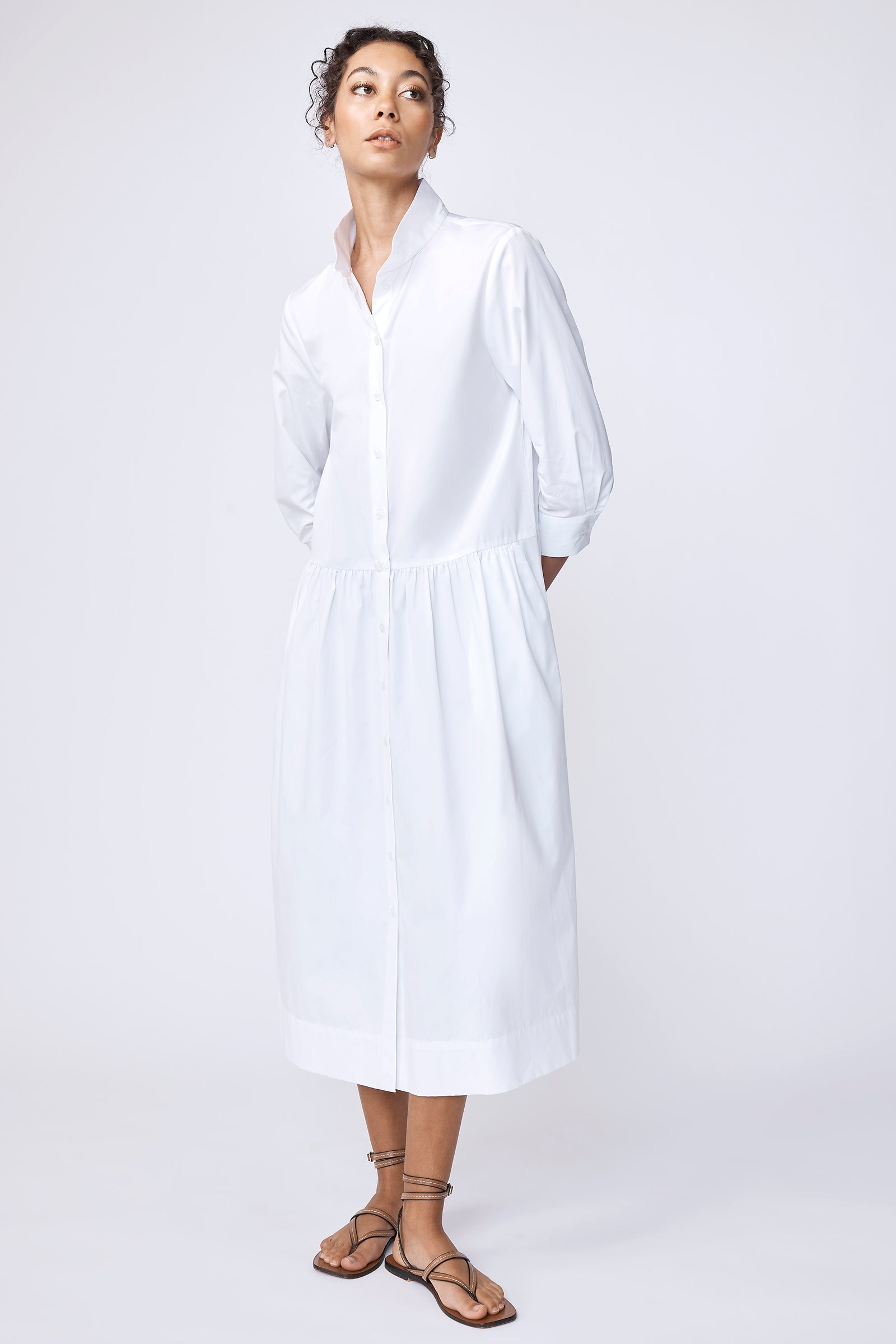 Kal Rieman Gemma Dress in white cotton poplin on model looking down touching cuff full front view