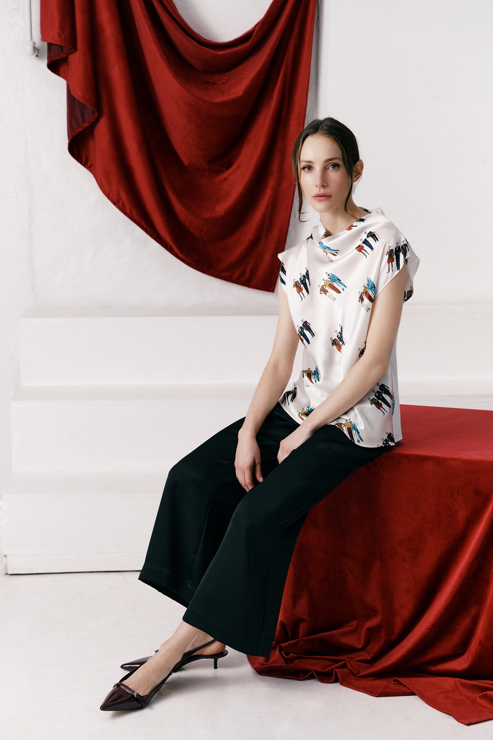 Woman wearing Kal Rieman Gloria Drape Top in Dandy Print and black pants on a white background hand in pocket arm on side, close view
