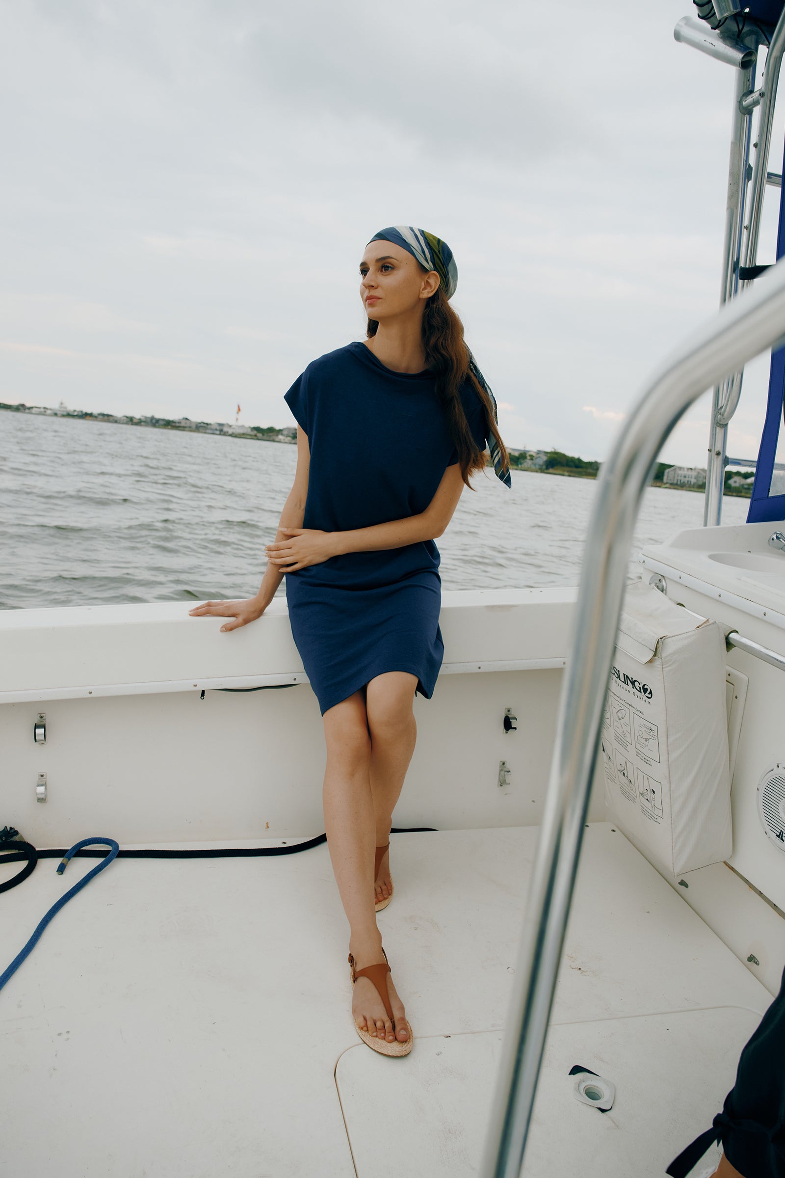 Kal Rieman Luca Cowl Dress in Navy on model sitting on boat full view