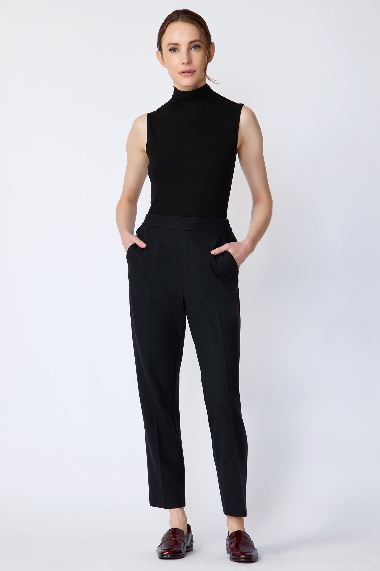 Woman wearing Kal Rieman Martine Trouser in midnight felted jersey with a black tank top and brown shoes, hands in pant pockets, full front view