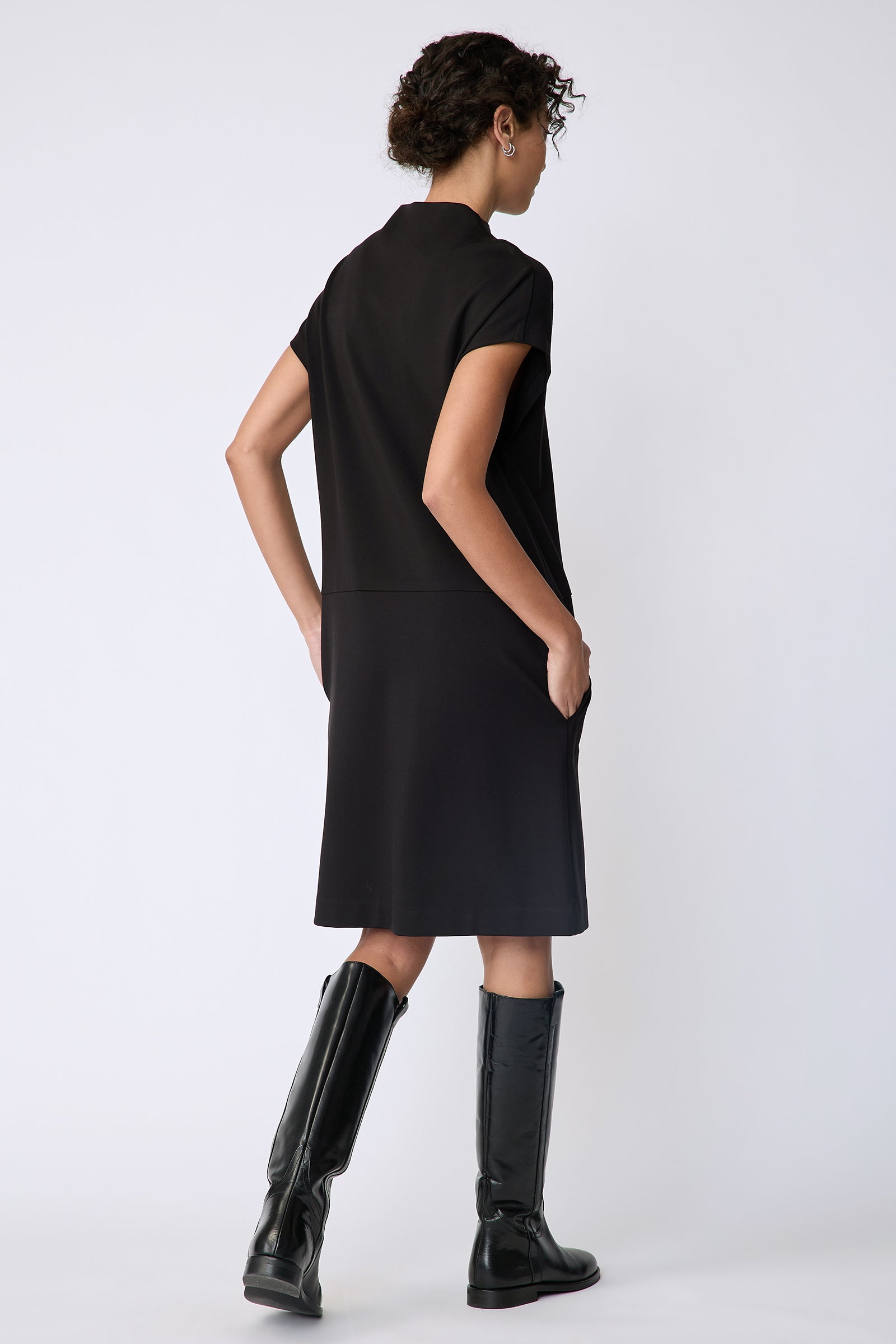 Kal Rieman Maya Funnelneck dress in black ponte on model front view walking hand in pocket