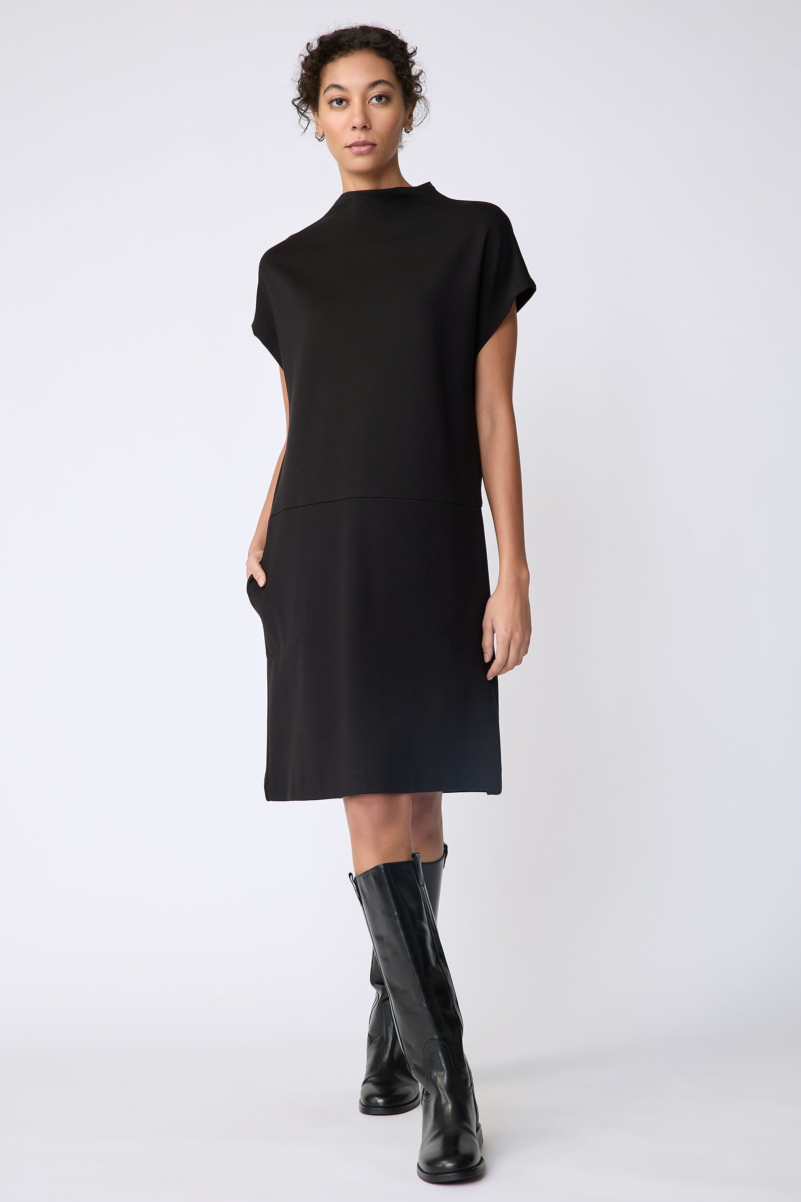 Kal Rieman Maya Funnelneck dress in black ponte on model front view walking hand in pocket