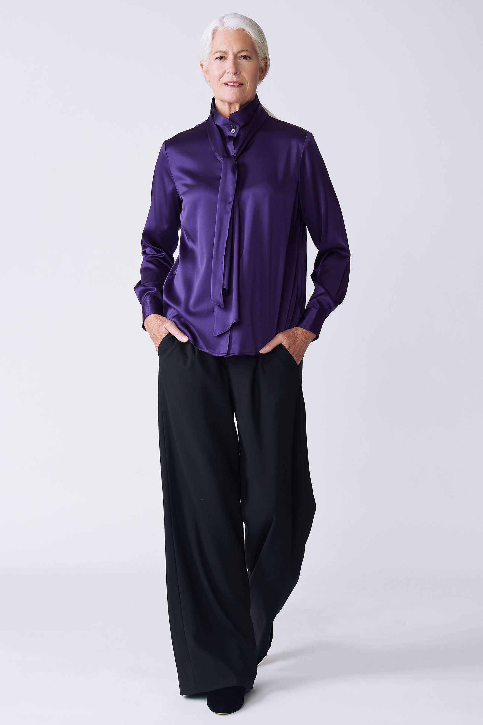 Kal Rieman Regency Silk Blouse in royal purple color charmeuse on model front view hands in pockets walking