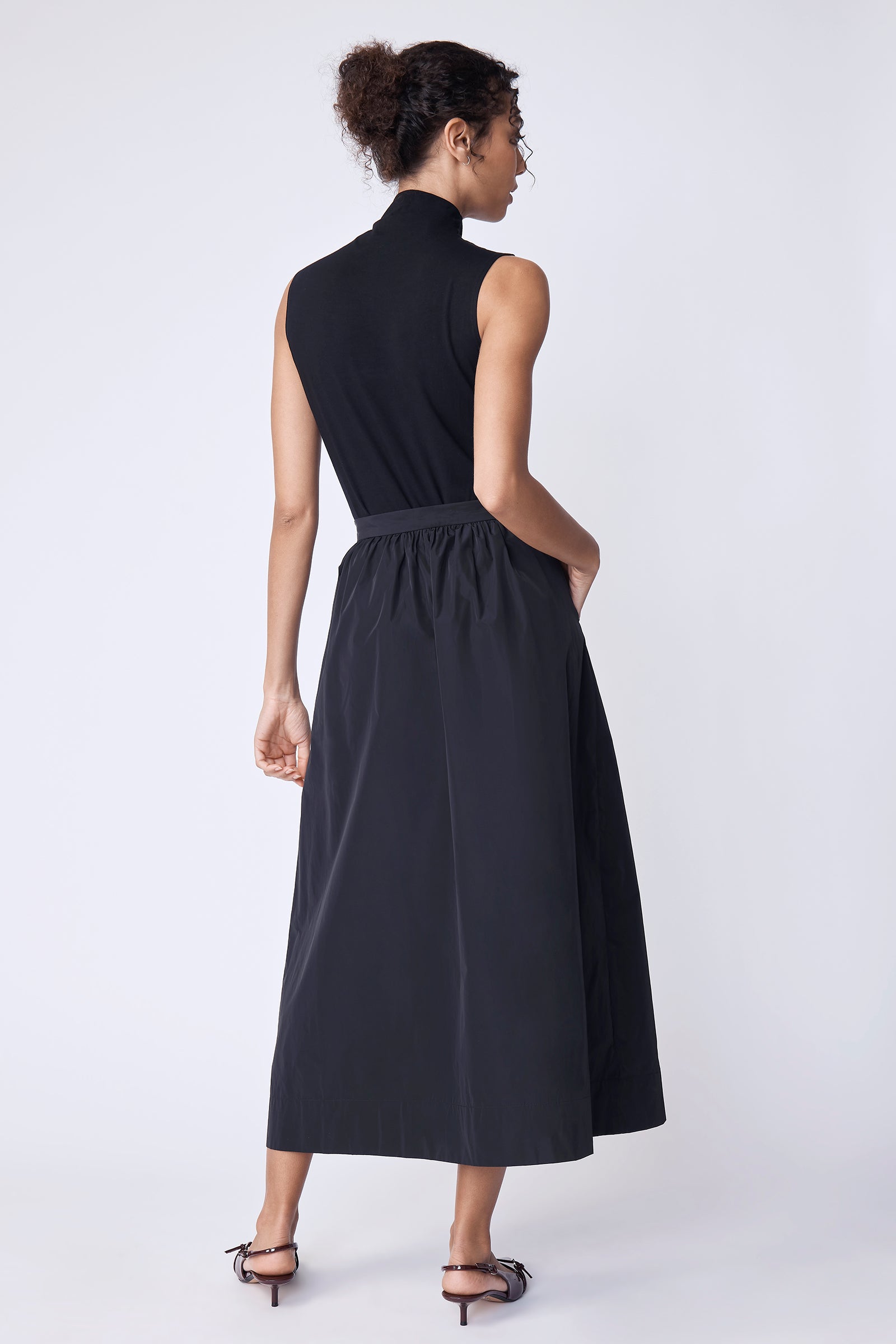 Woman wearing a burgundy sweater and black skirt against a white background