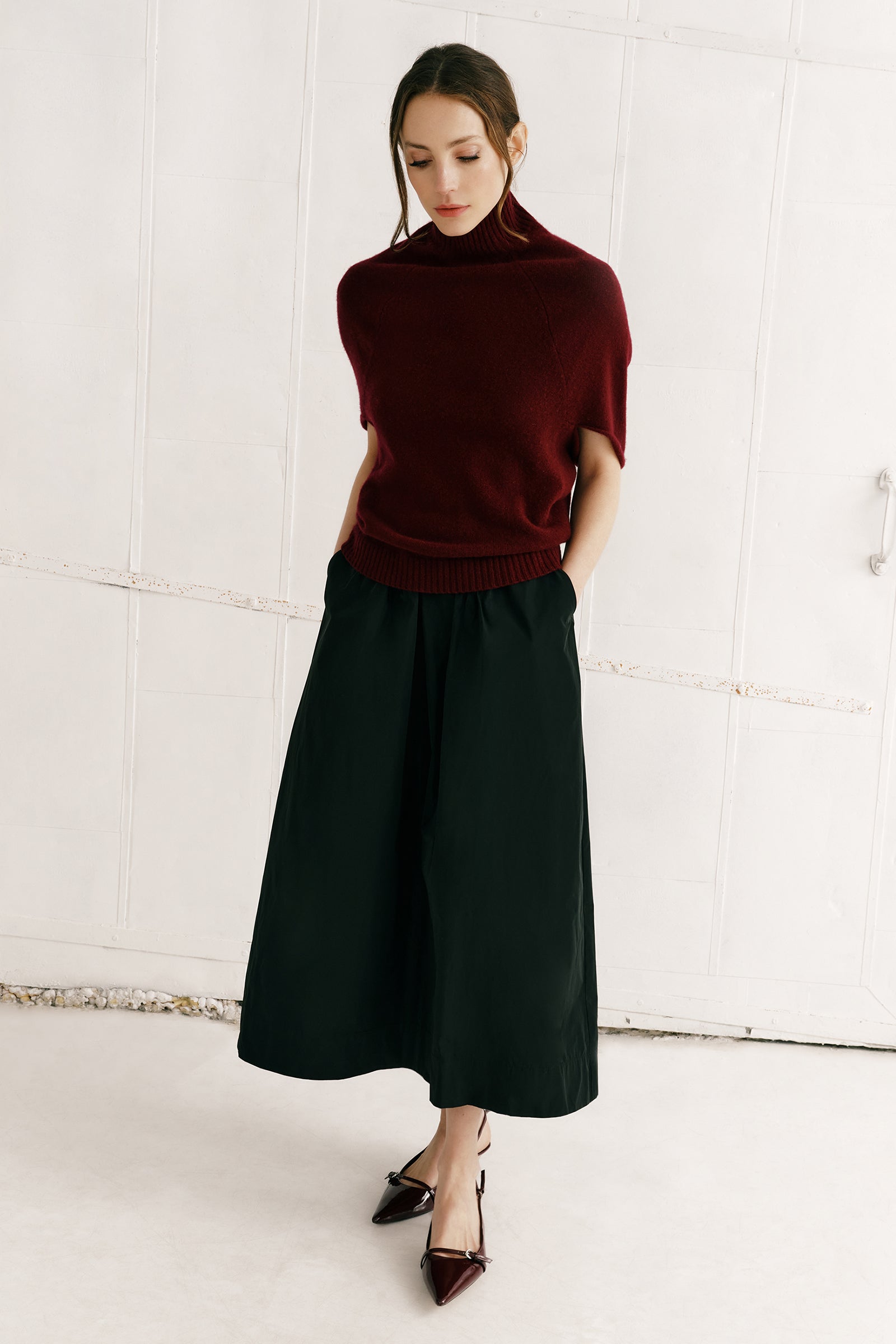 Woman wearing a burgundy sweater and black skirt against a white background
