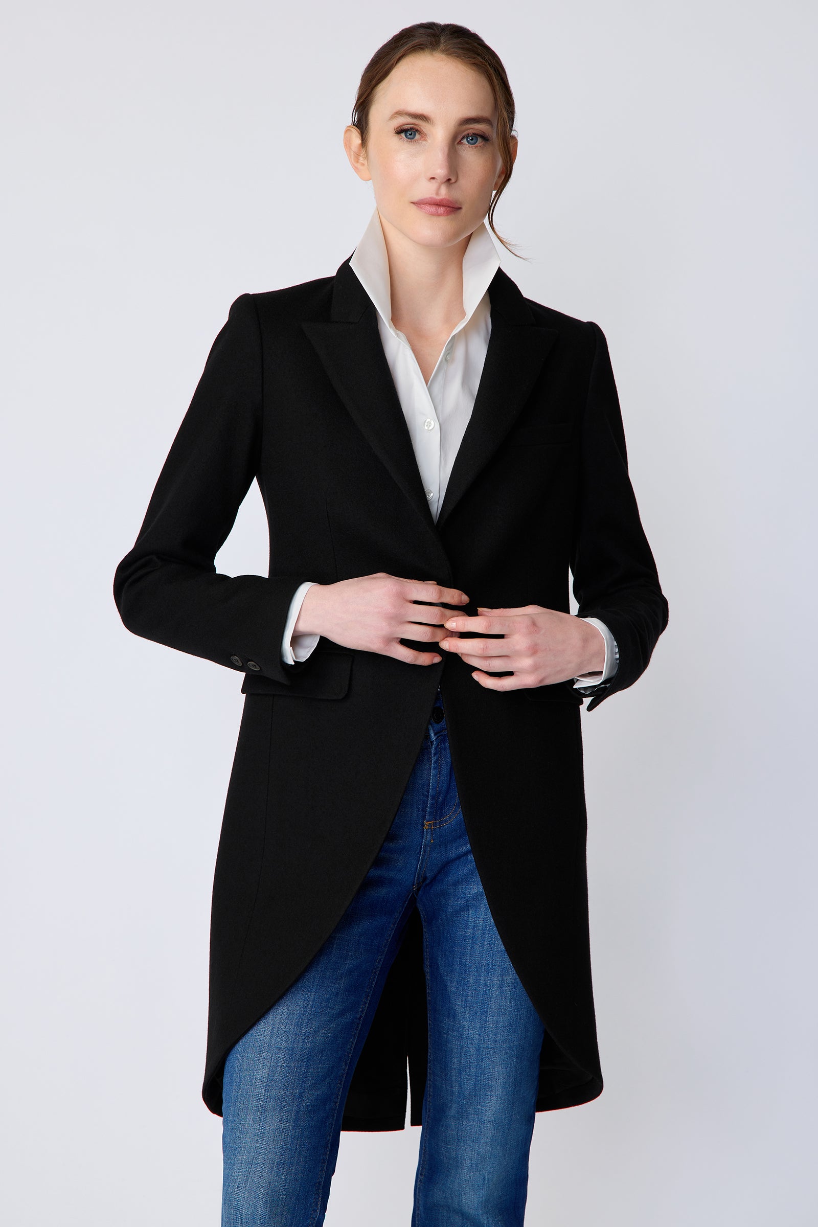 Woman wearing Kal Rieman Tailored Tux Blazer in Black, Collar unfolded, with blue jeans, hands holding the button in the front, close view