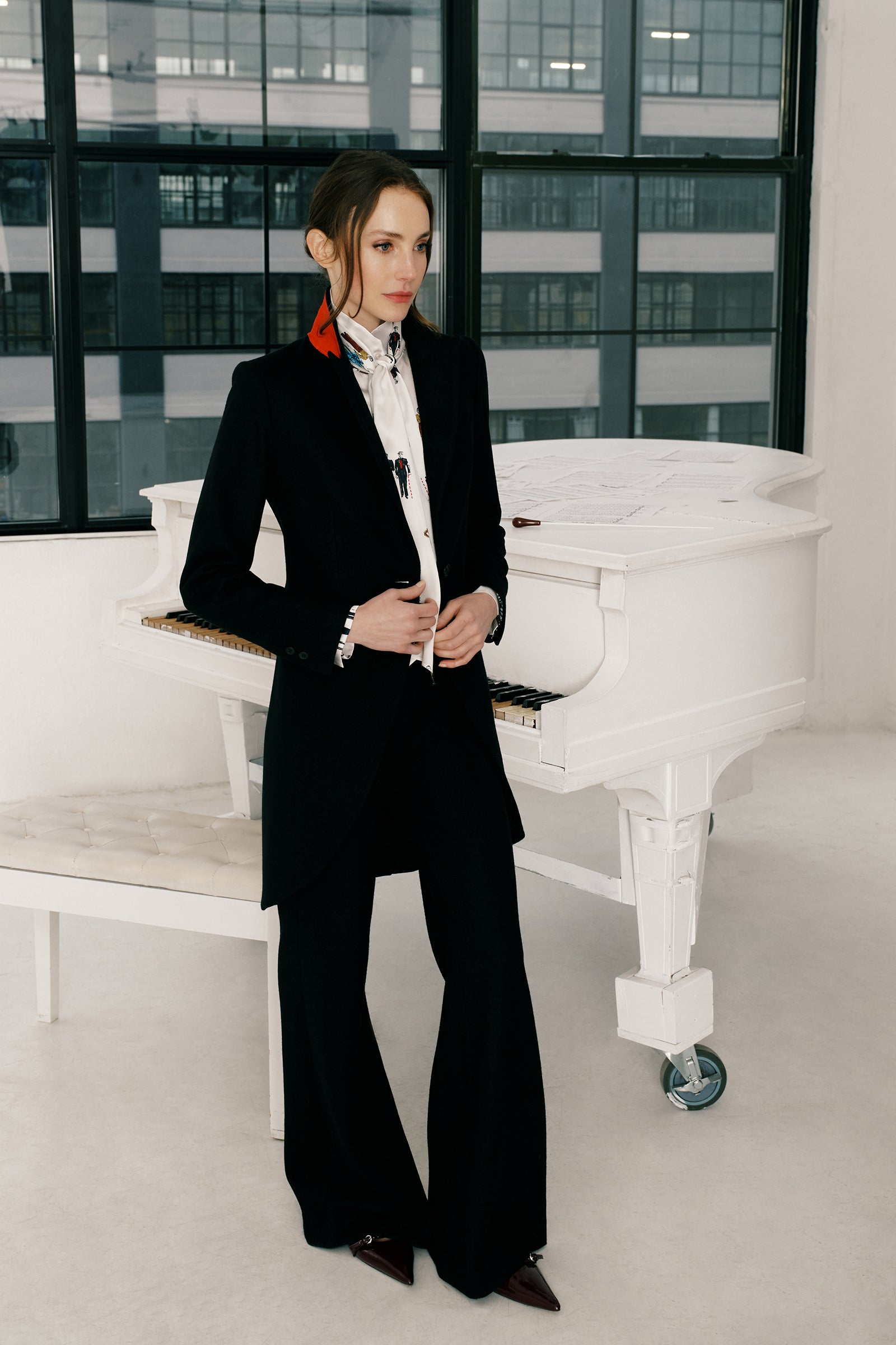 Woman wearing Kal Rieman Tailored Tux Blazer in Black, Collar unfolded, with blue jeans, hands holding the button in the front, close view