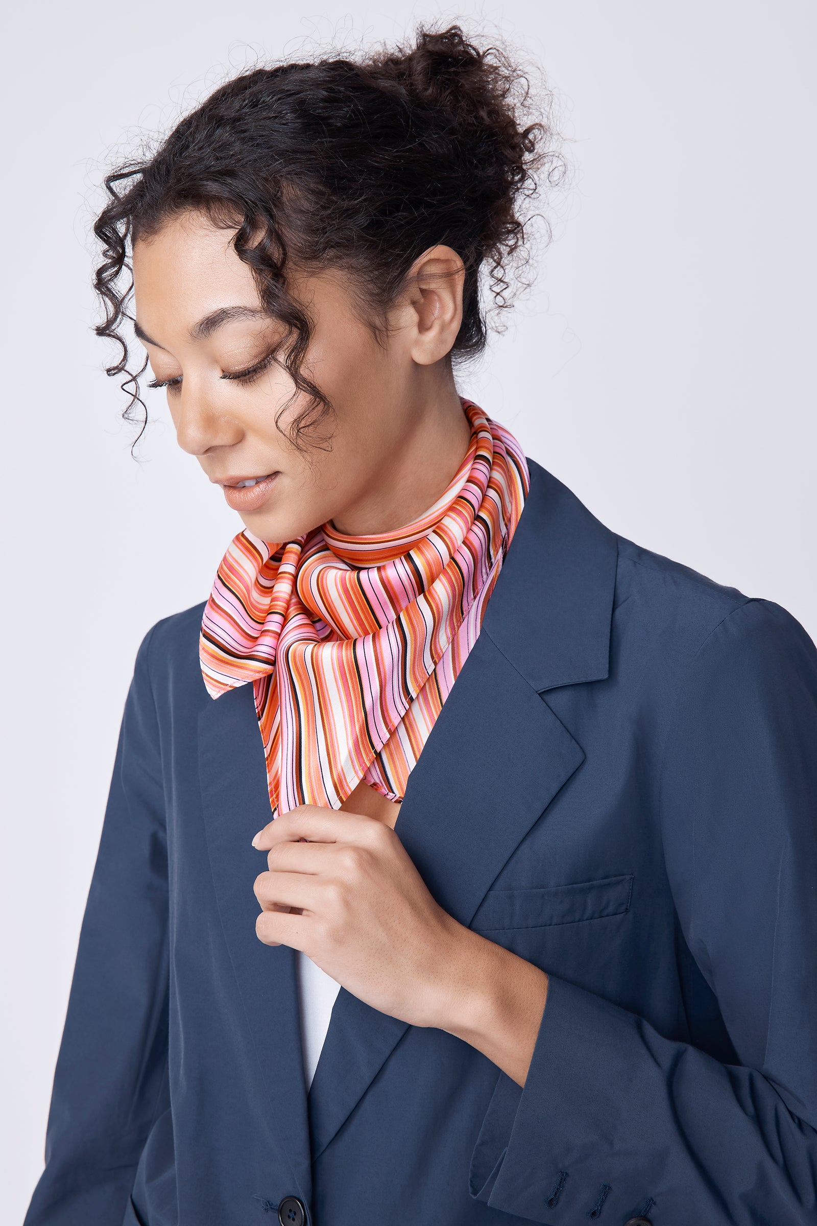 Kal Rieman Scarf in Capri Silk on model holding scarf wearing a navy blazer front view