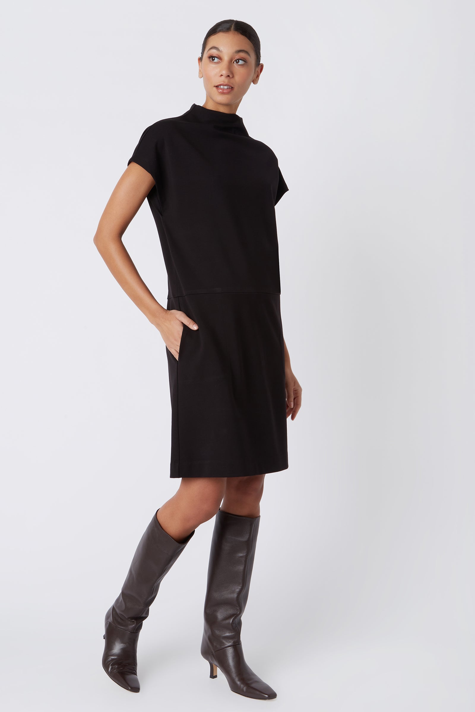Kal Rieman Maya Funnel Dress in Black Ponte on Model Walking with Hand in Pocket Full Front Side View
