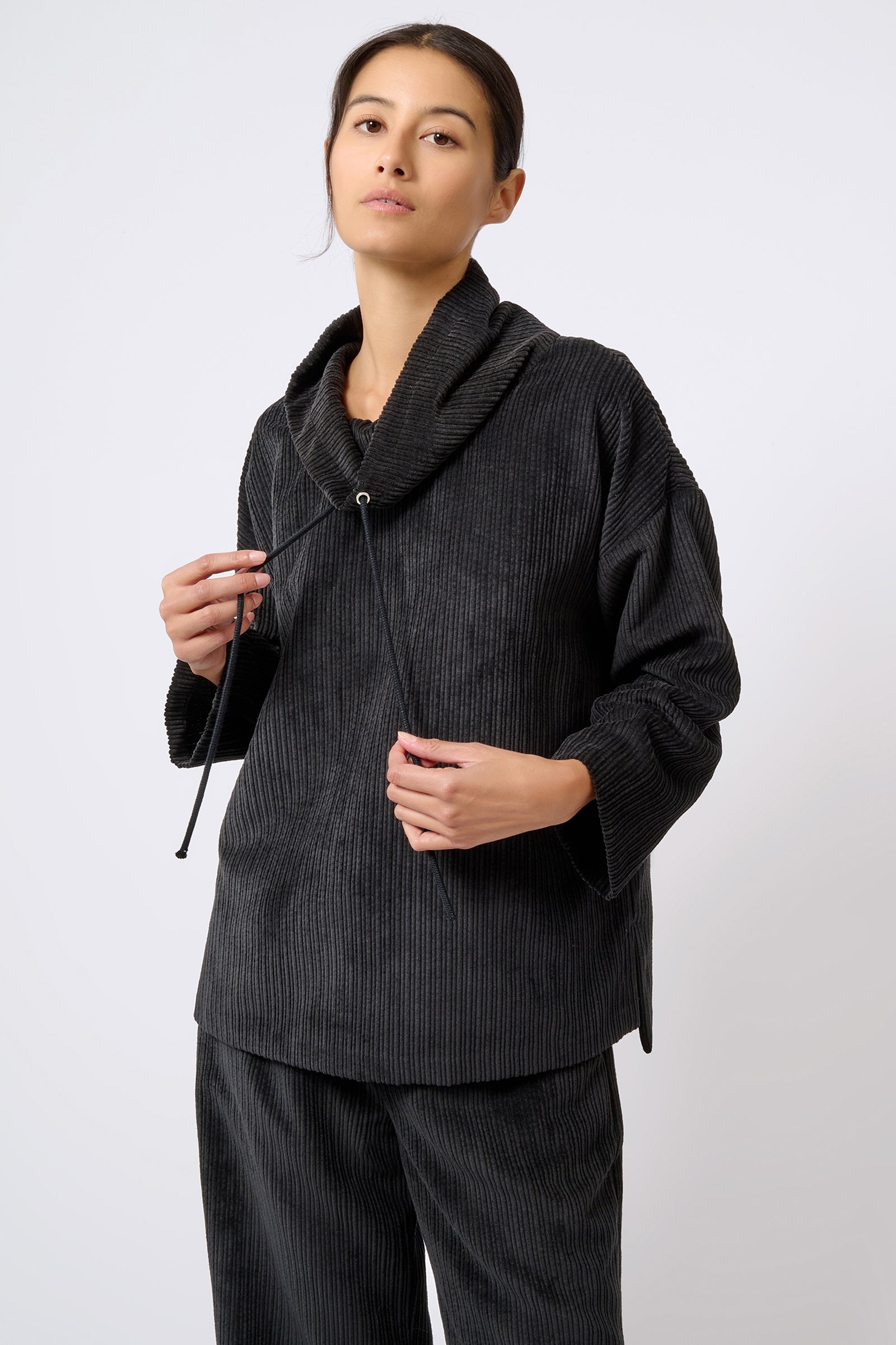 Kal Rieman Debbie Drawstring Pullover in Black on Model with Hand on Drawstring Front View